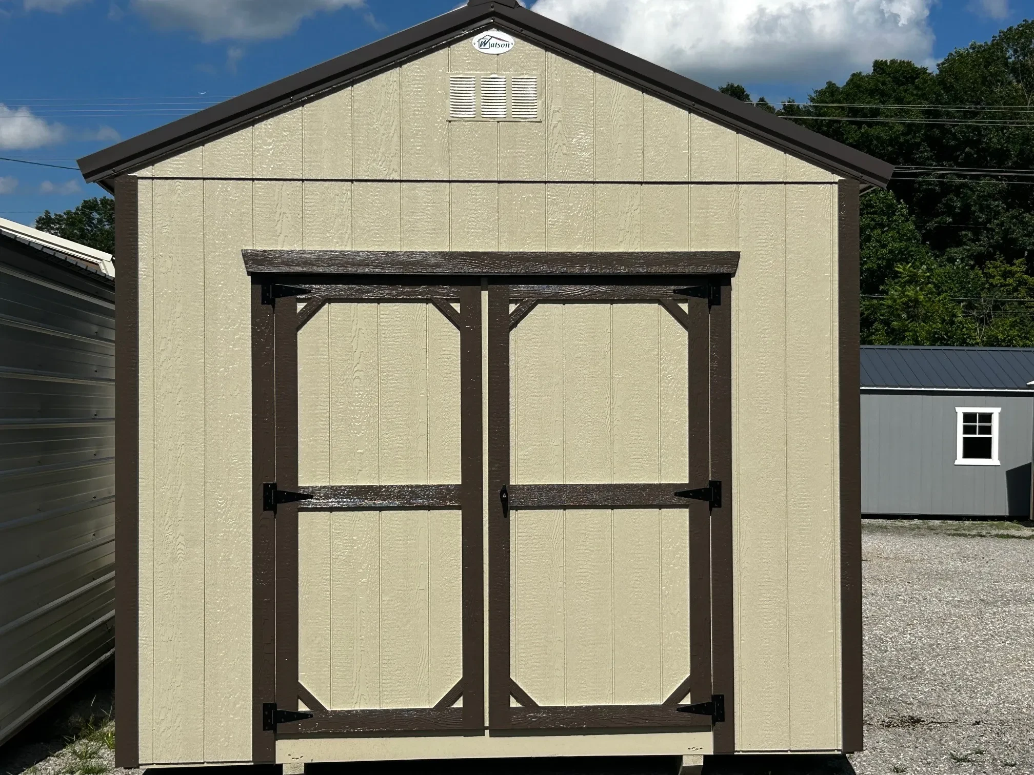 the front of a wood shed painted a light stone color