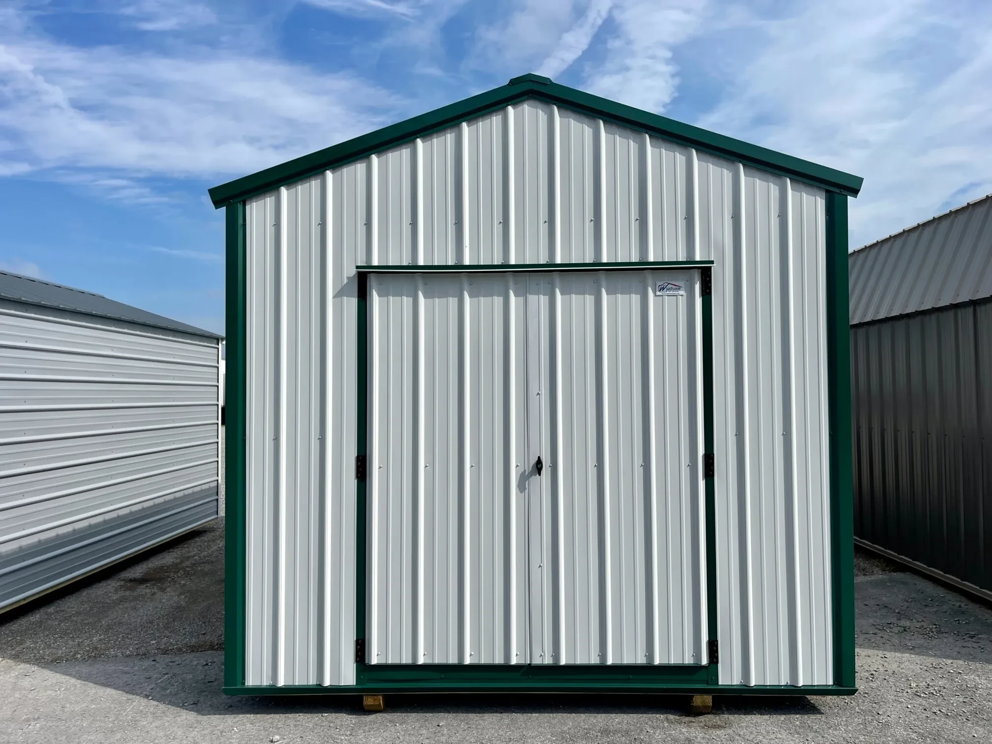 a white metal shed with green trim