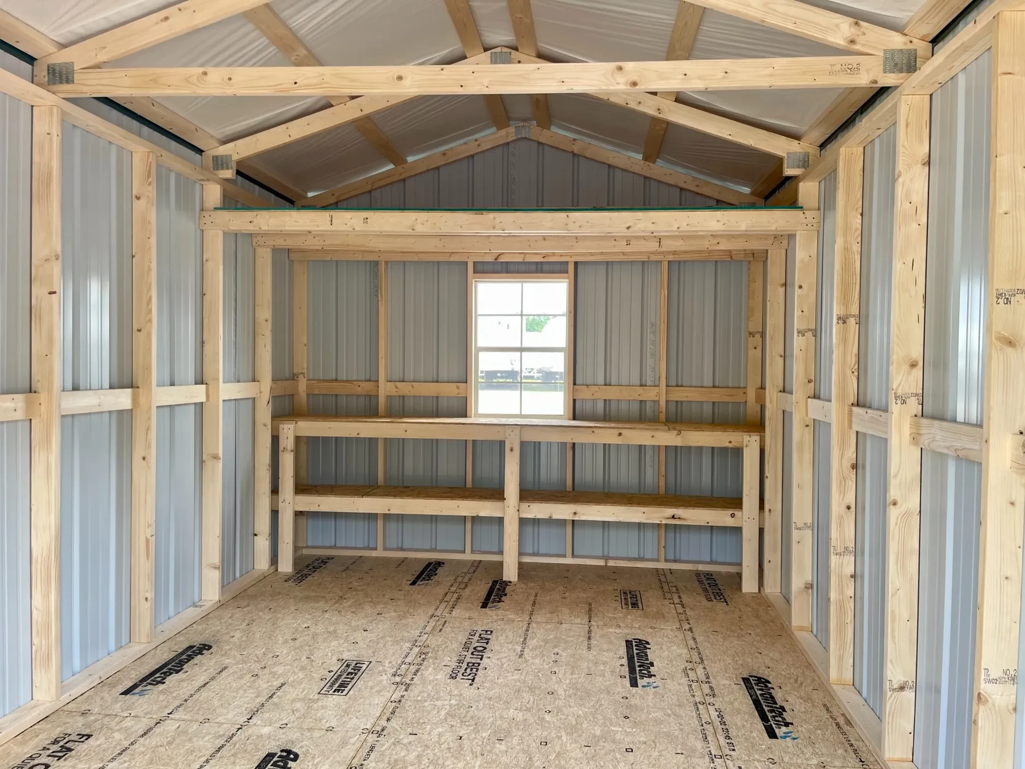 the inside of a metal shed with double shelves, a window, and a loft
