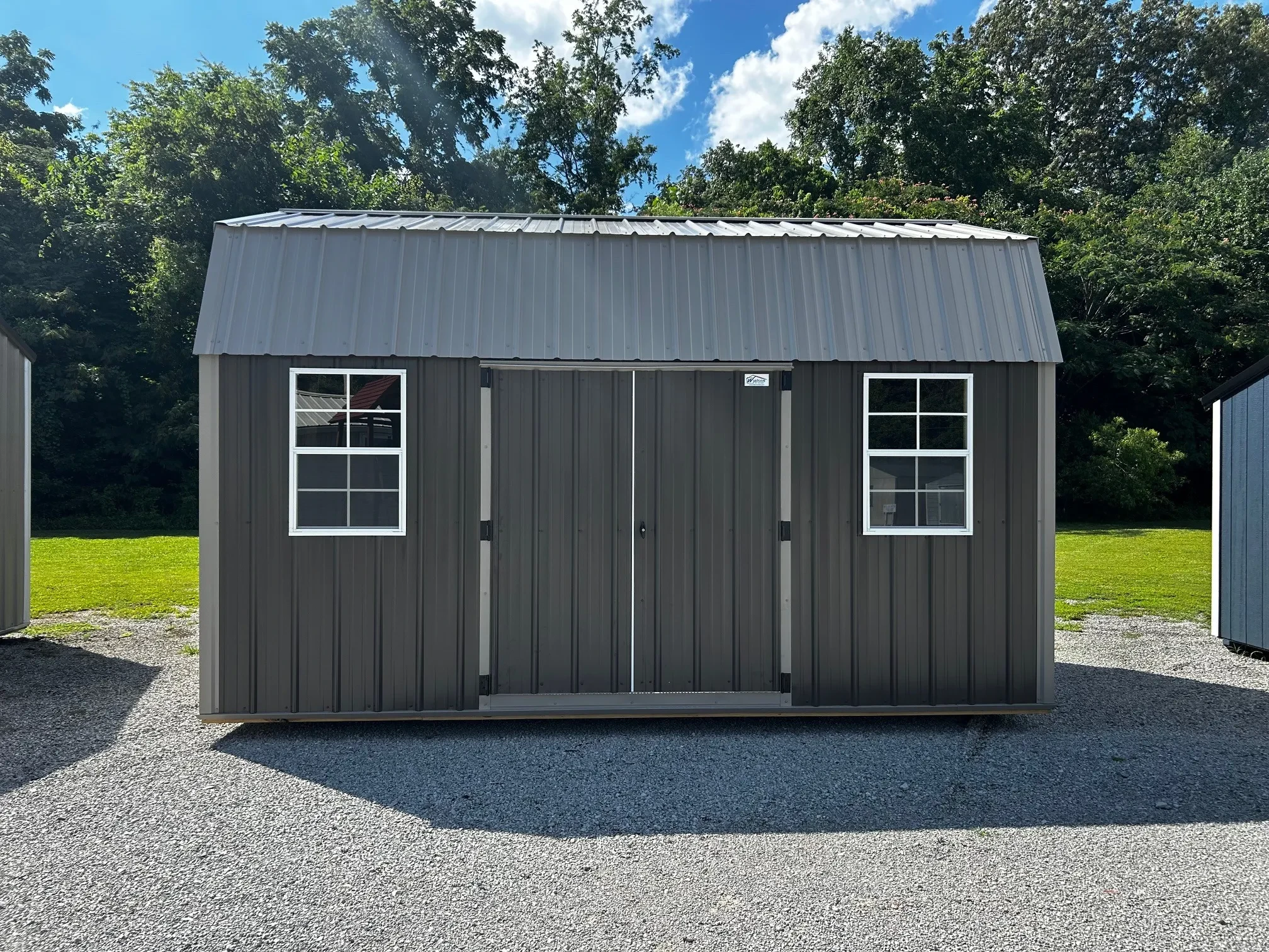 a metal lofted barn with windows and the door on the side