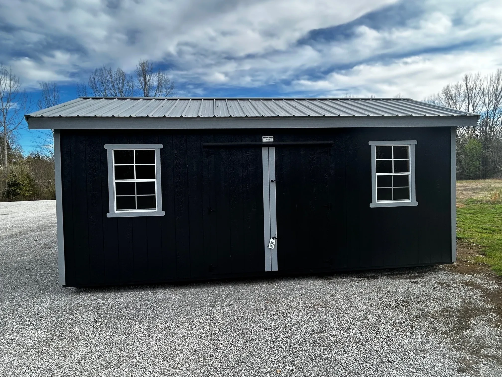 a black garden shed with two windows and an overhang on all sides