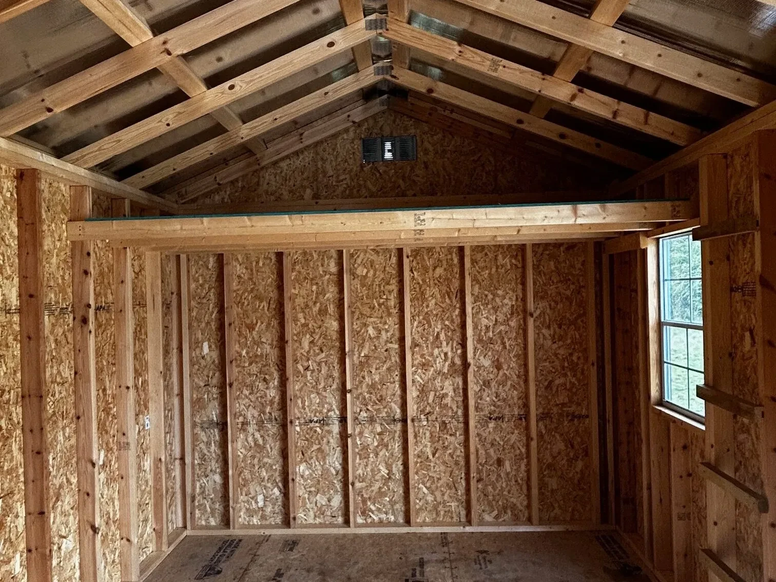 a loft and a window inside a wood garden shed