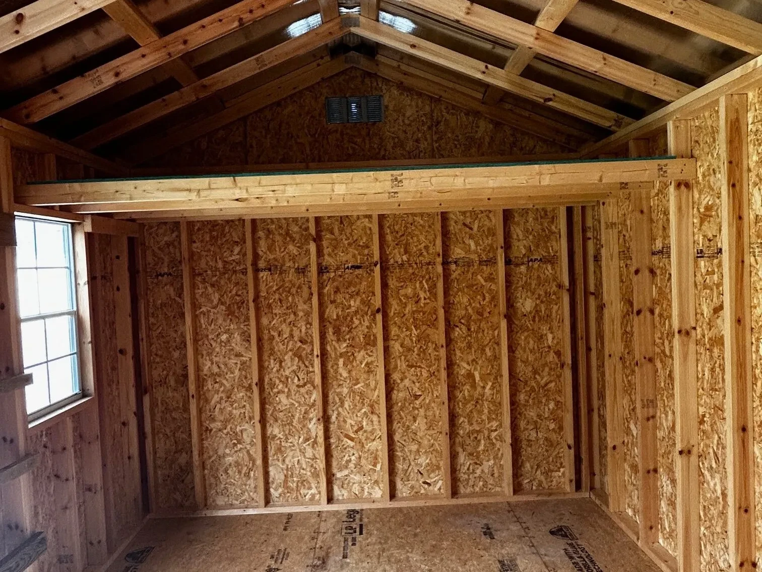 a loft and a window inside a wood garden shed
