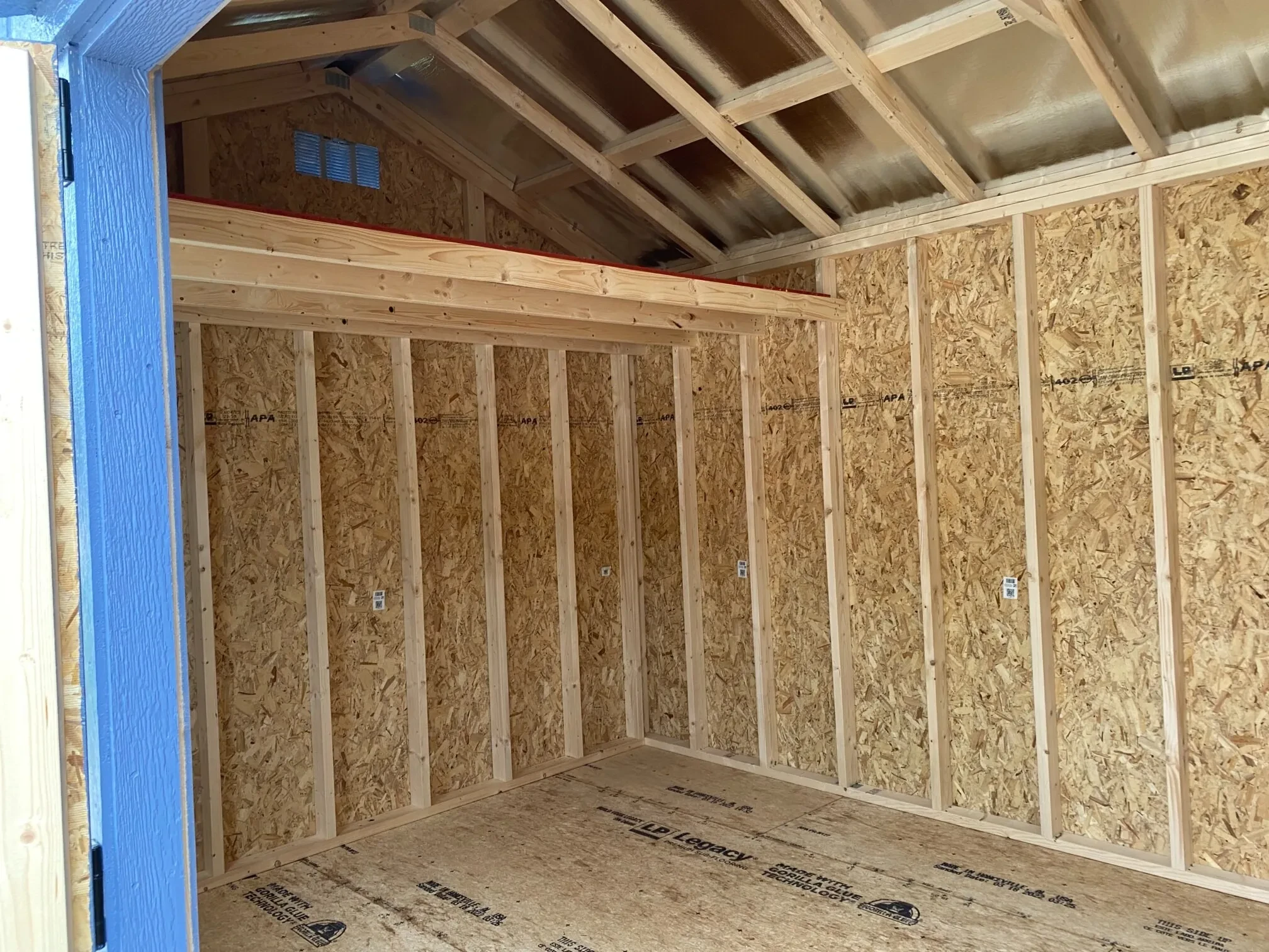 the inside of a wood garden shed showing a loft and a vent