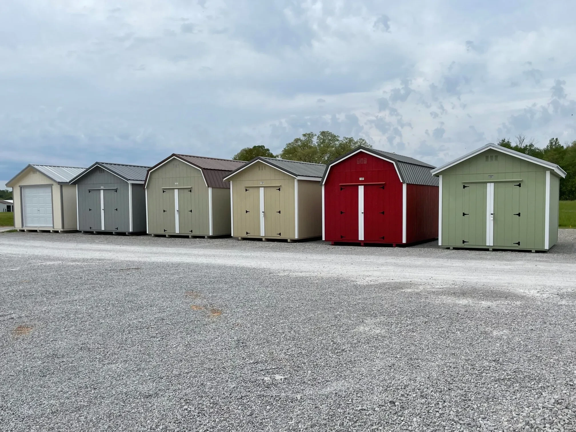 row of colorful premium wood tennessee sheds on a gravel lot