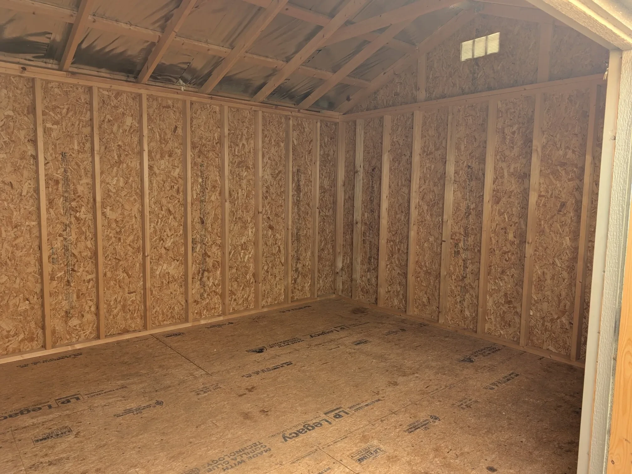 the inside of a wood shed showing the floor and walls
