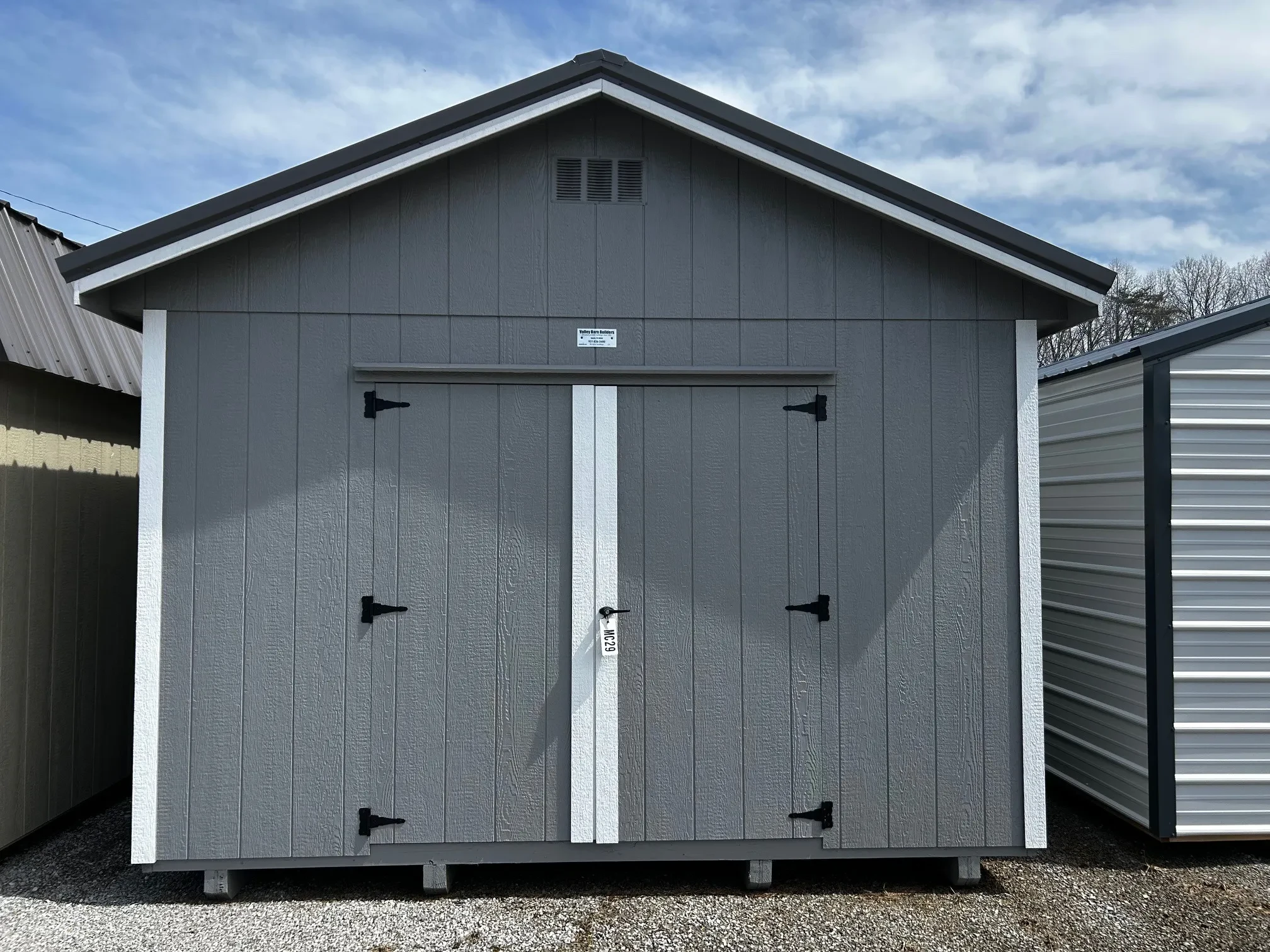 the front of a wood shed with double doors painted light gray