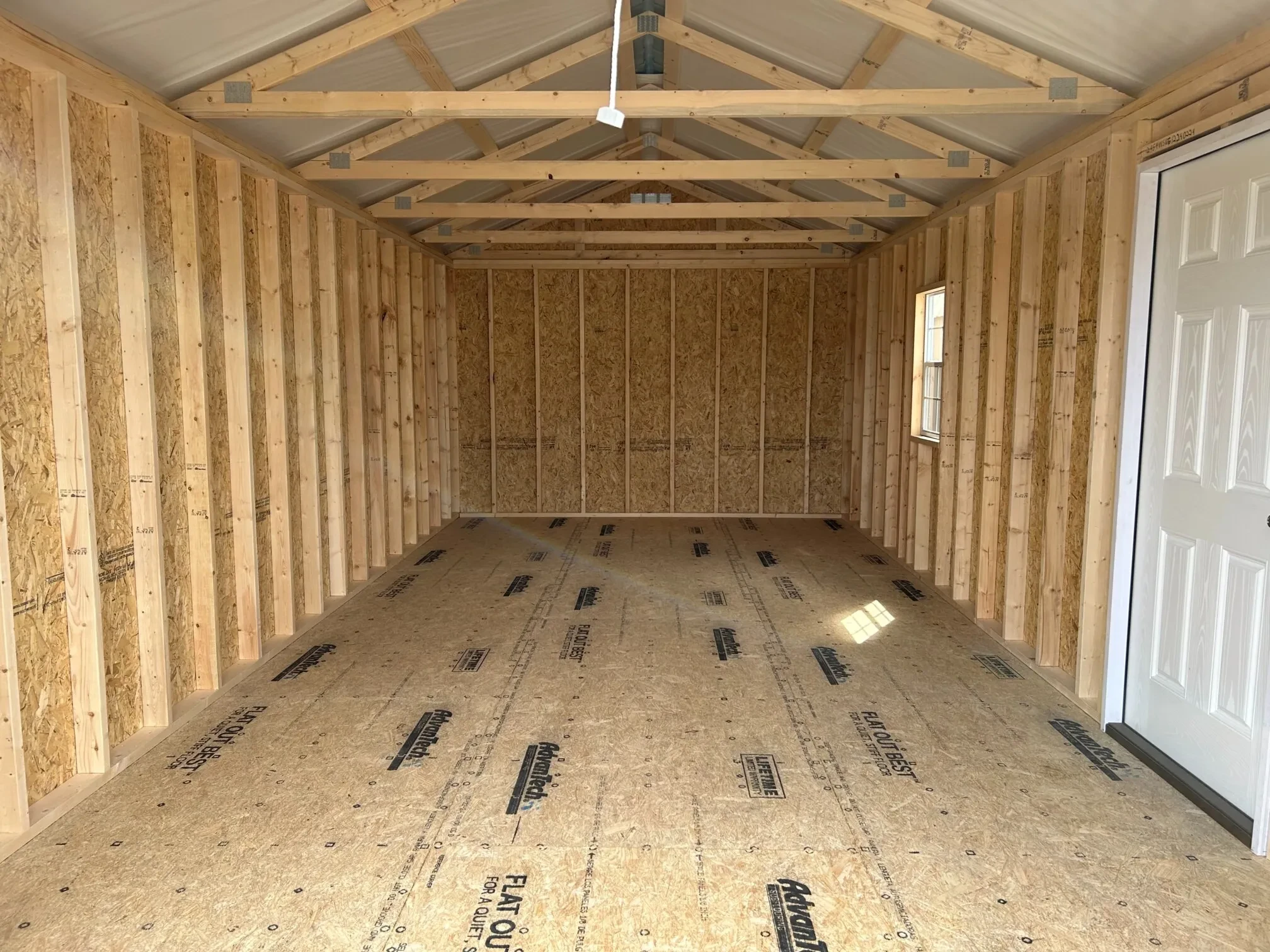 the inside of a wood garage shed showing a window and a walk in door