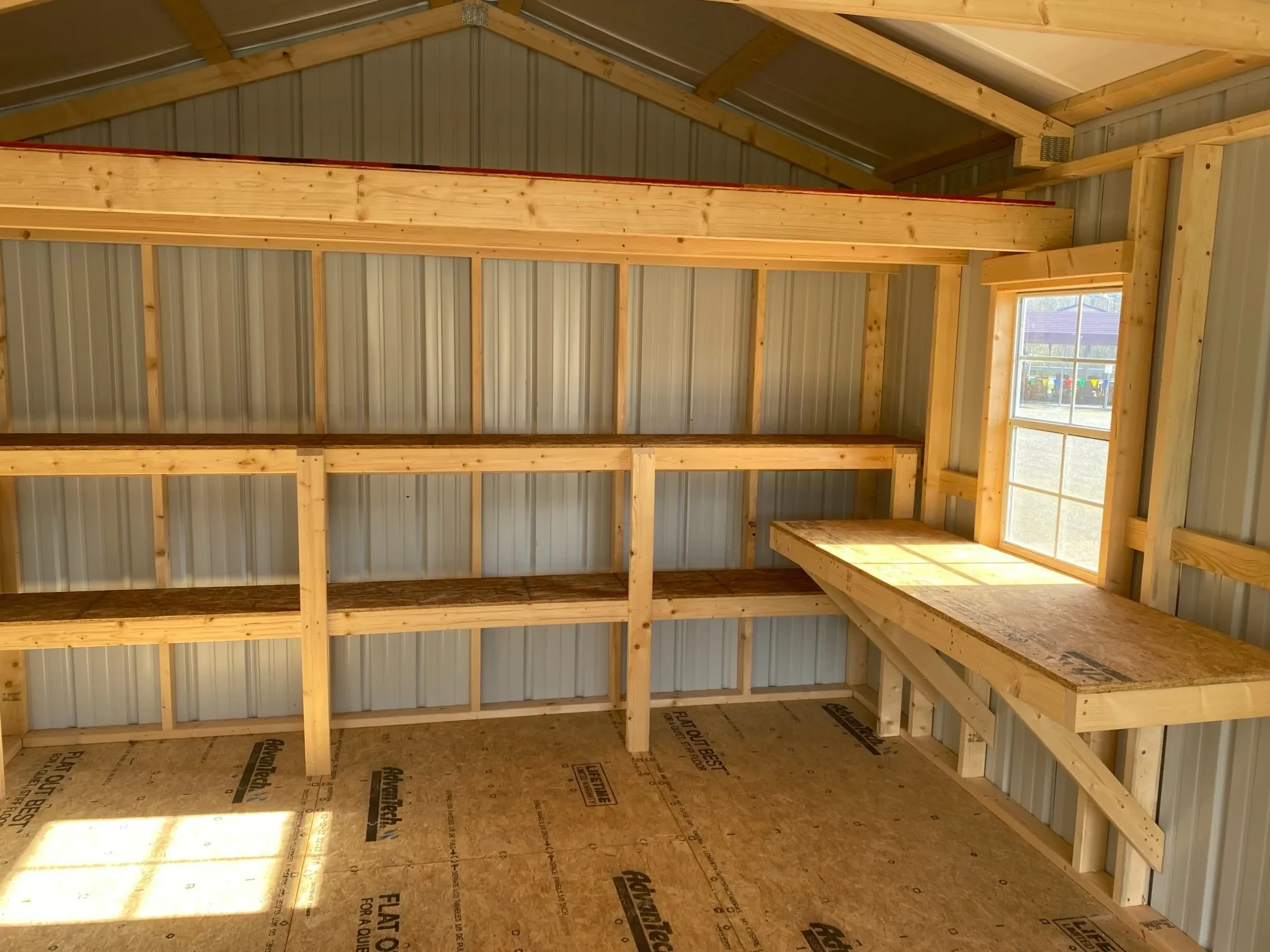 a loft, double shelves, a window, and a workbench inside a metal garage