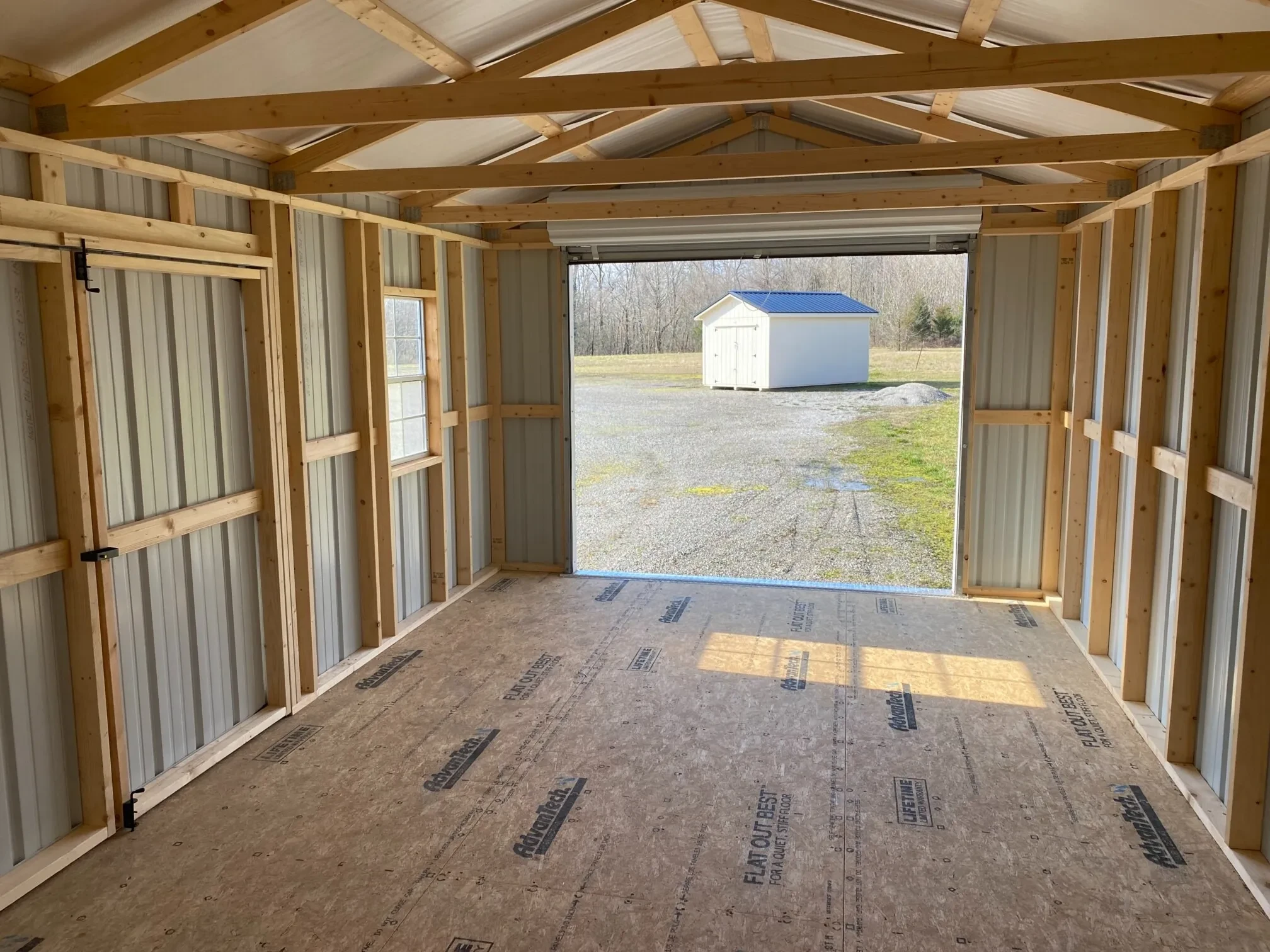 looking out a rollup garage door that is open from inside a metal garage shed