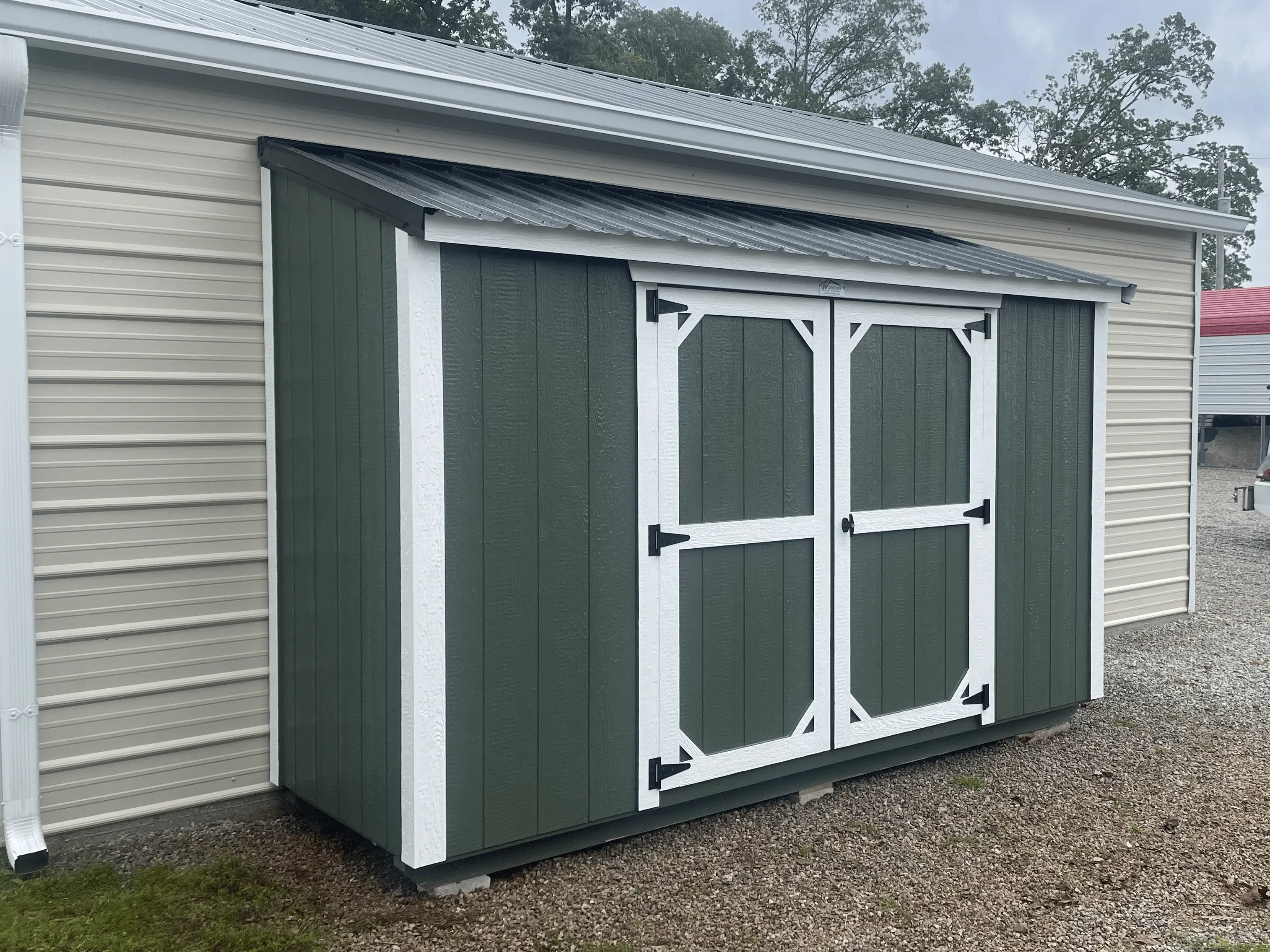 Green leanto shed against a garage.