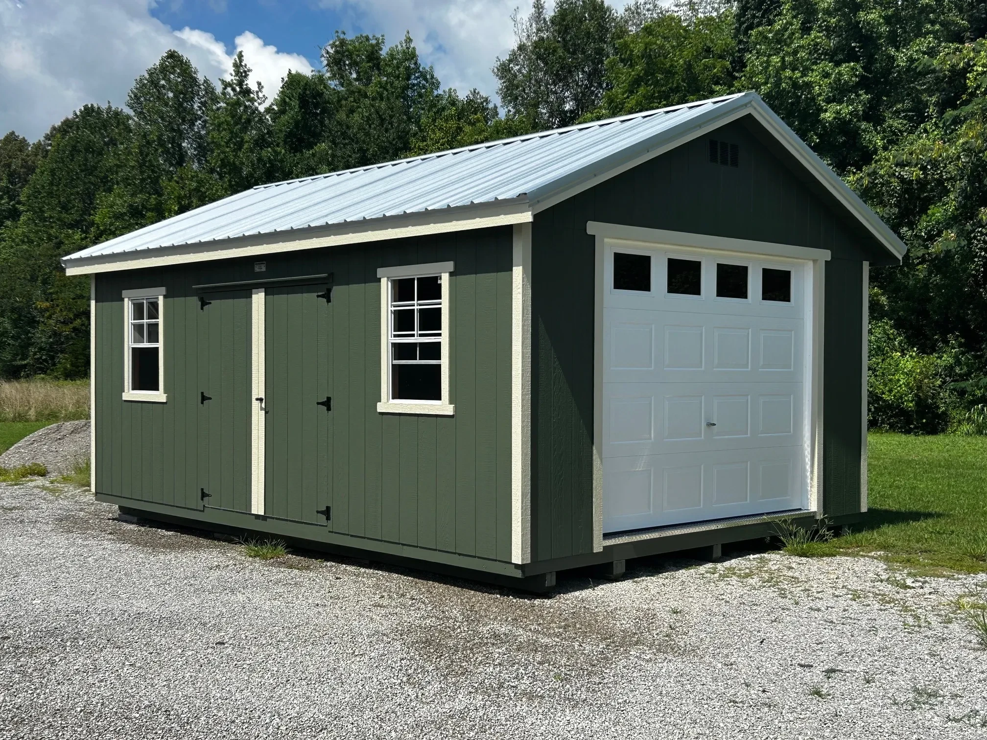 a green wood garage shed with an overhang and windows and double doors