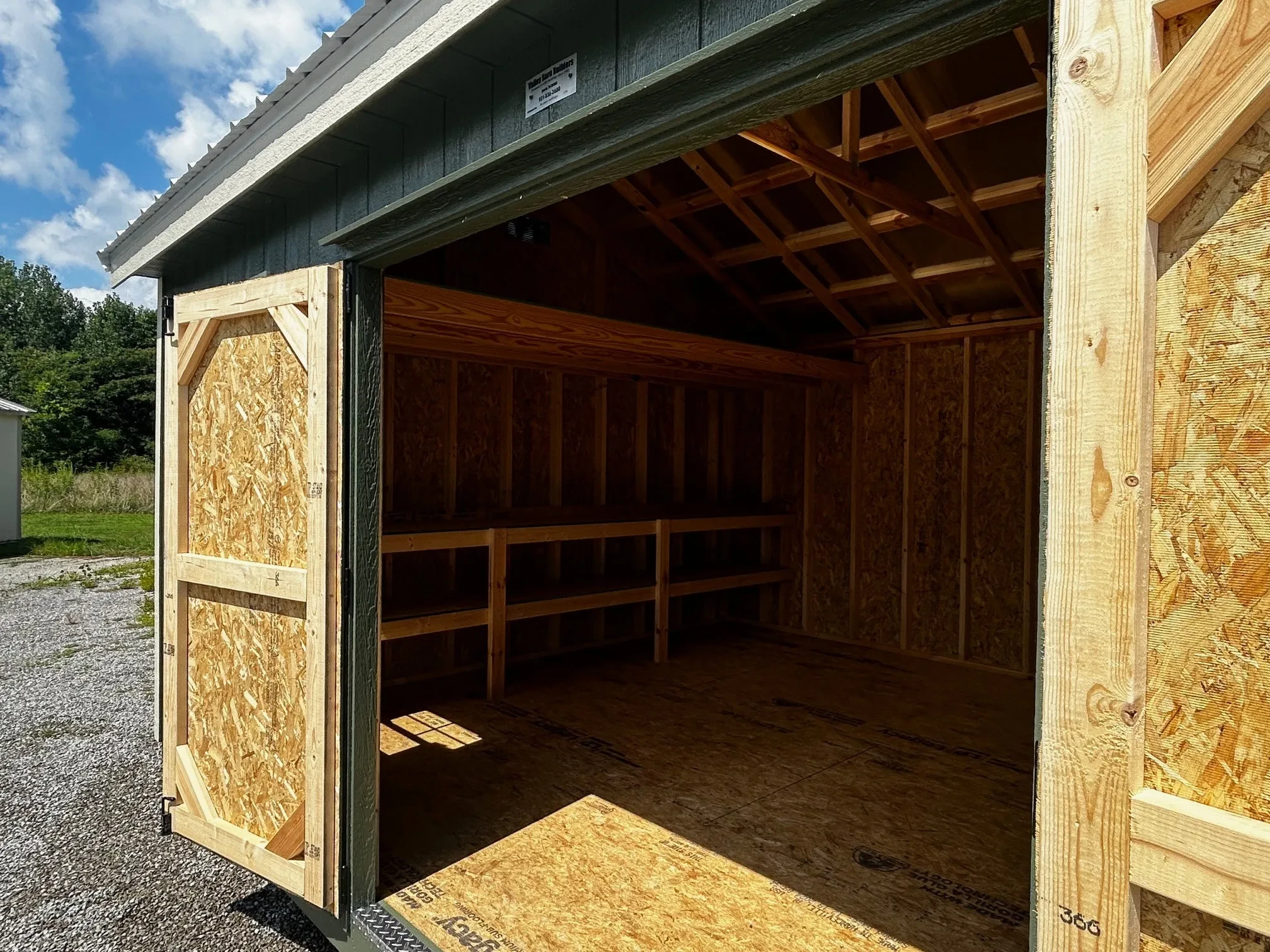 the inside of a wood shed showing double shelves and a loft on the back wall