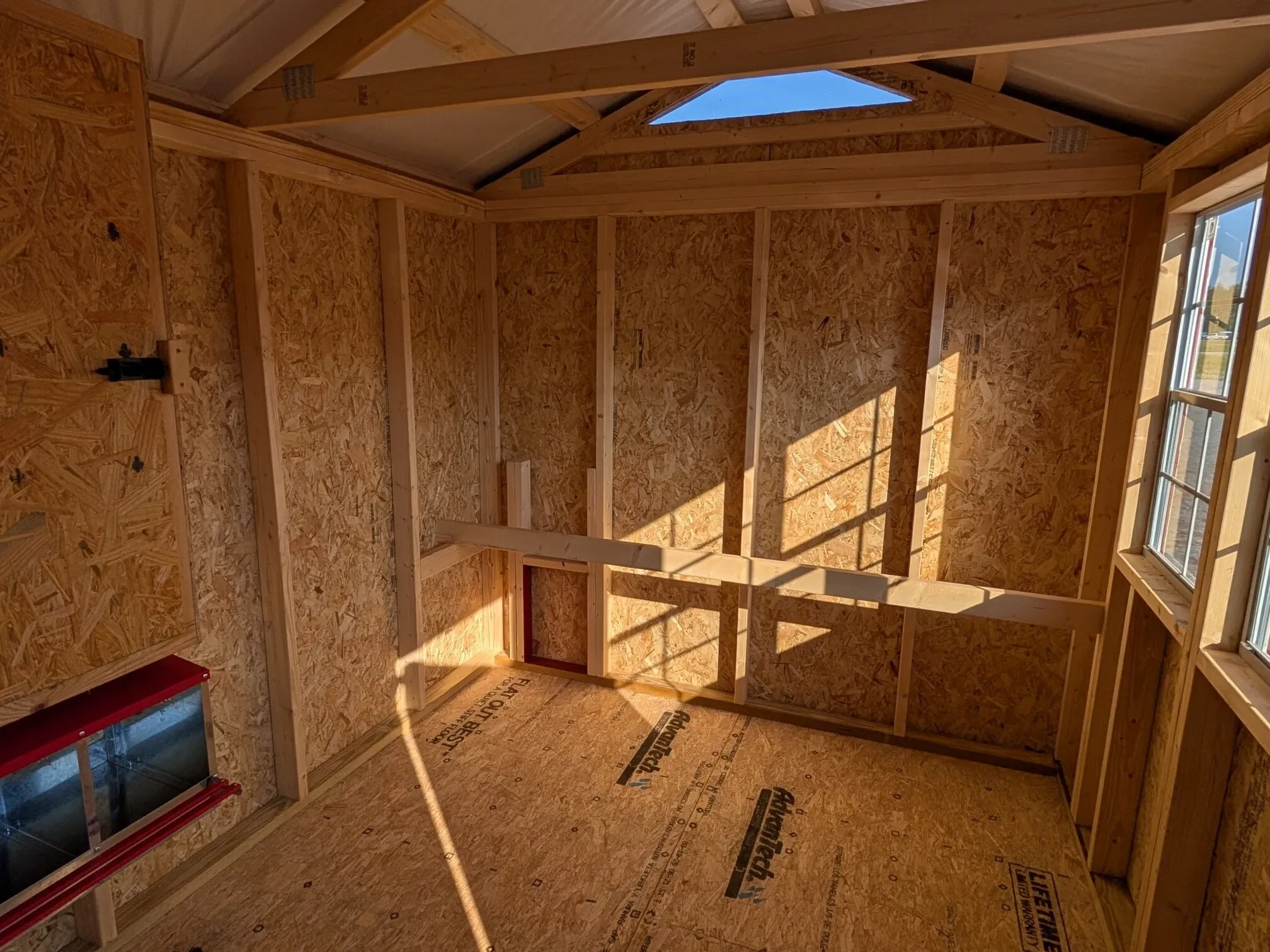 inside a wood chicken coop with a roosting bar and chicken door