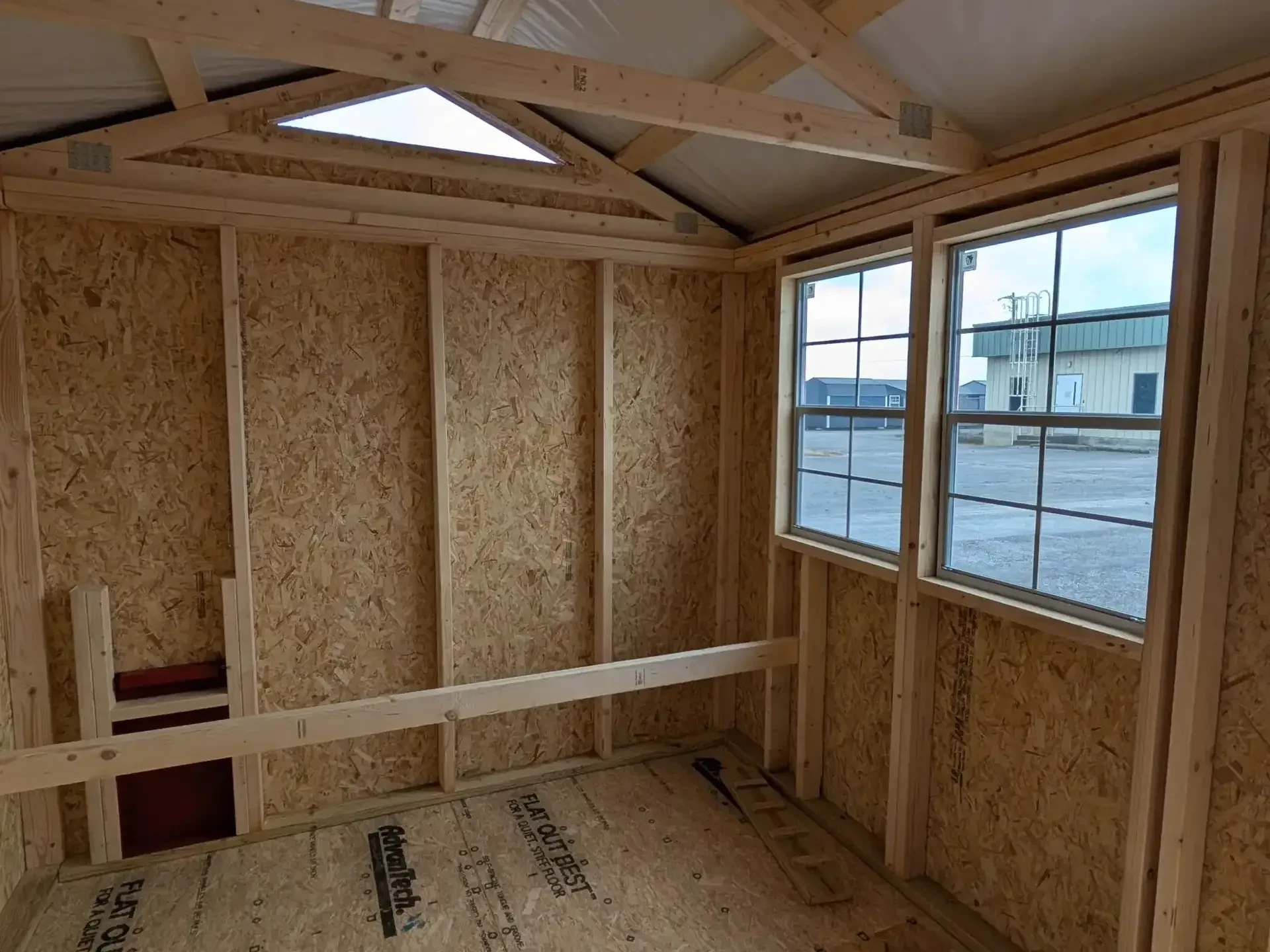 inside a chicken coop with two windows and a roosting bar