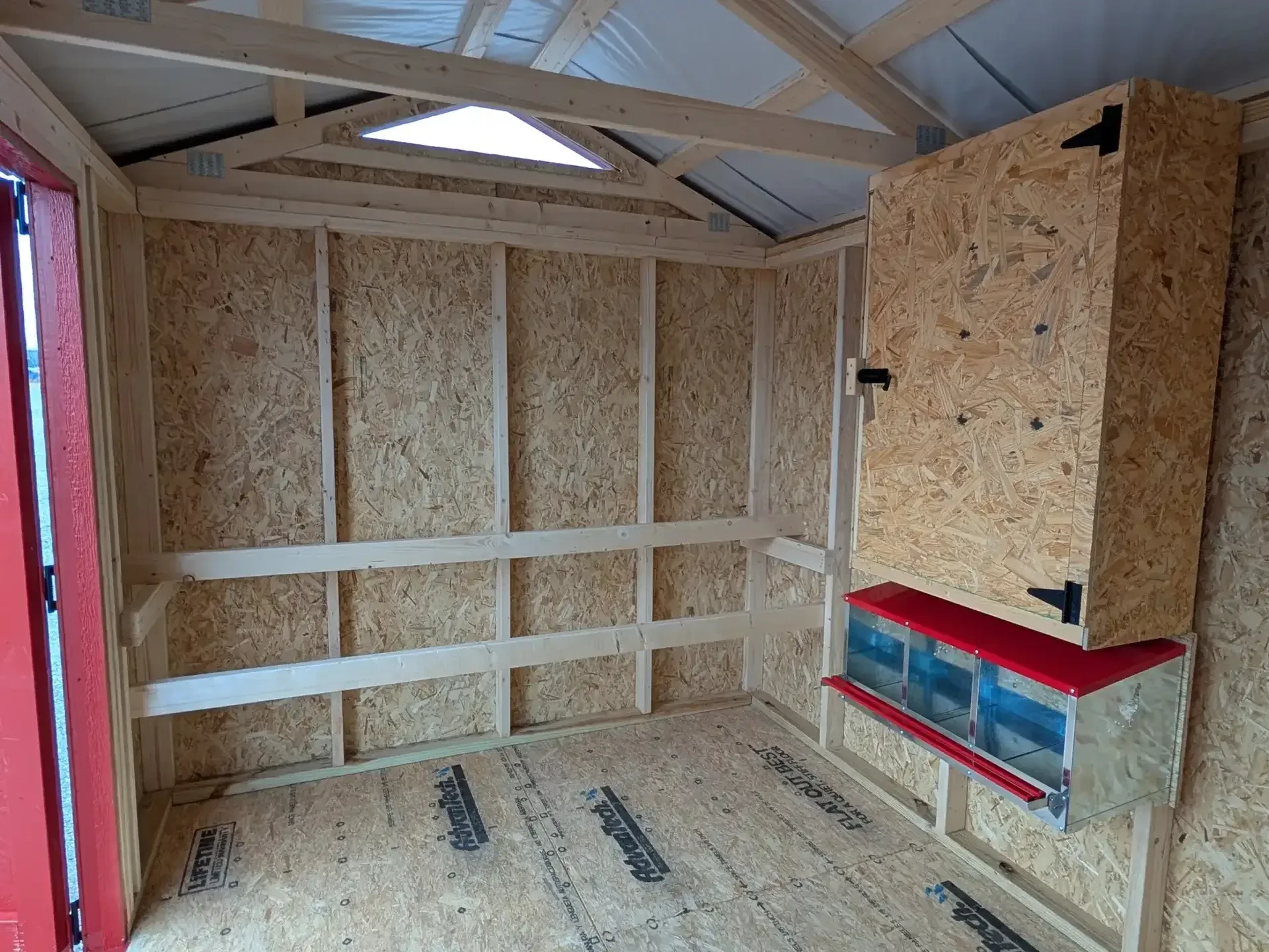 inside of a chicken coop with multiple roosting bars, nesting boxes and a storage cabinet