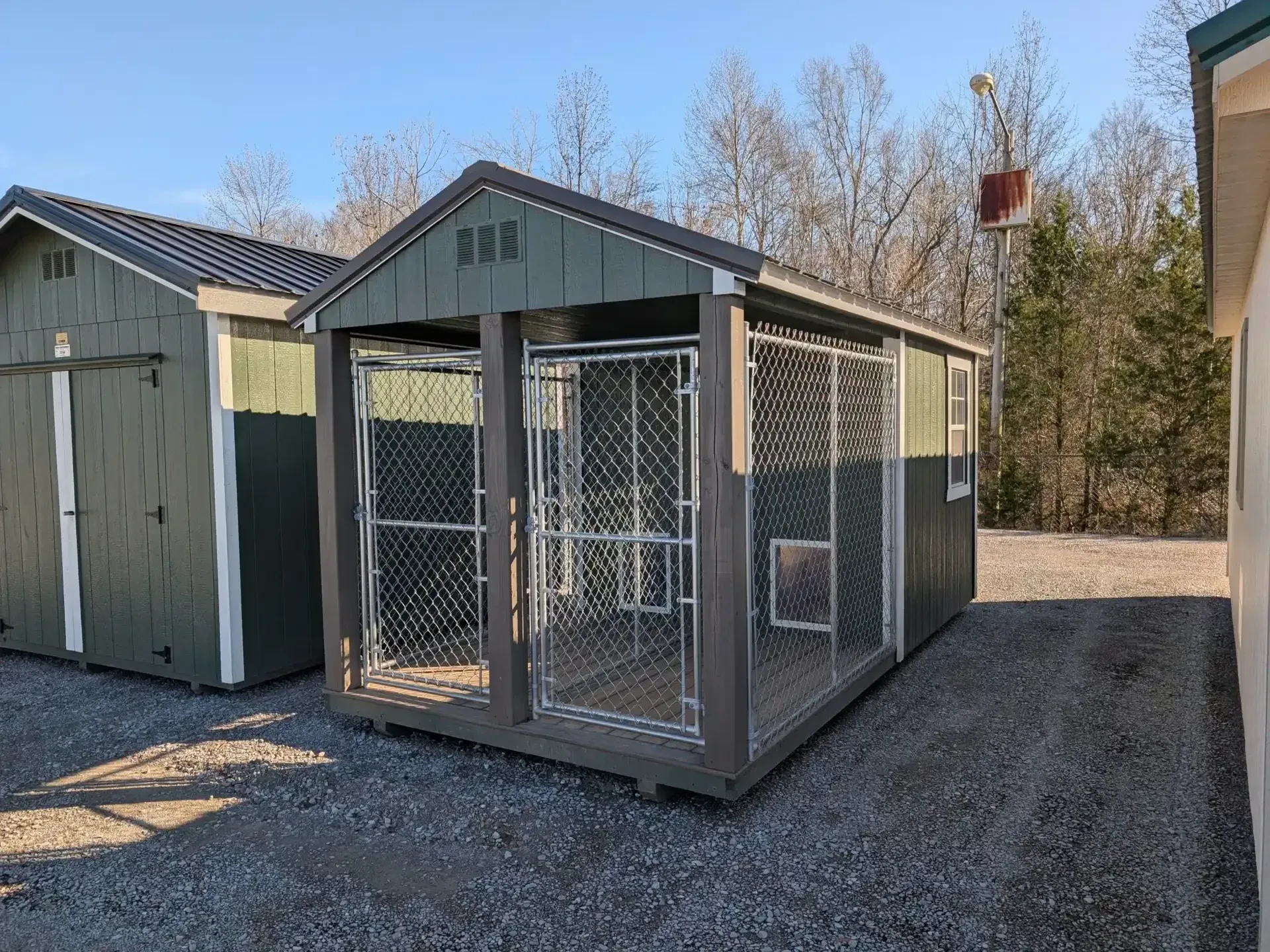 a dog kennel with two bays closed in by a chain link run
