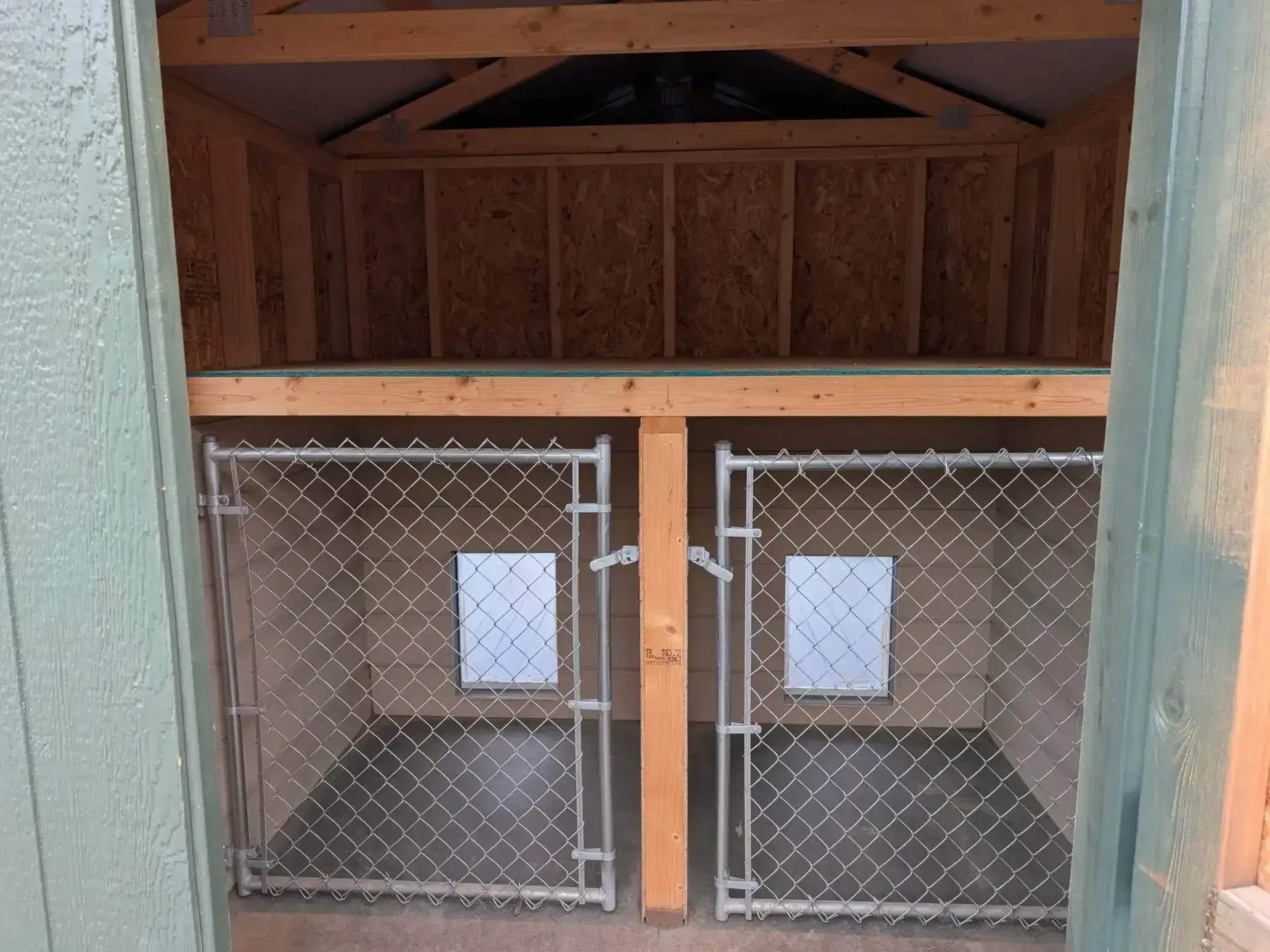 inside a dog kennel with two chain link gates for dog to go into