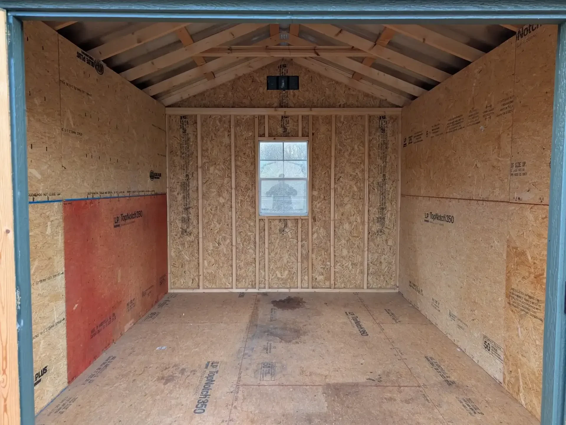 the inside of a wood shed with plywood on the walls holding in insulation