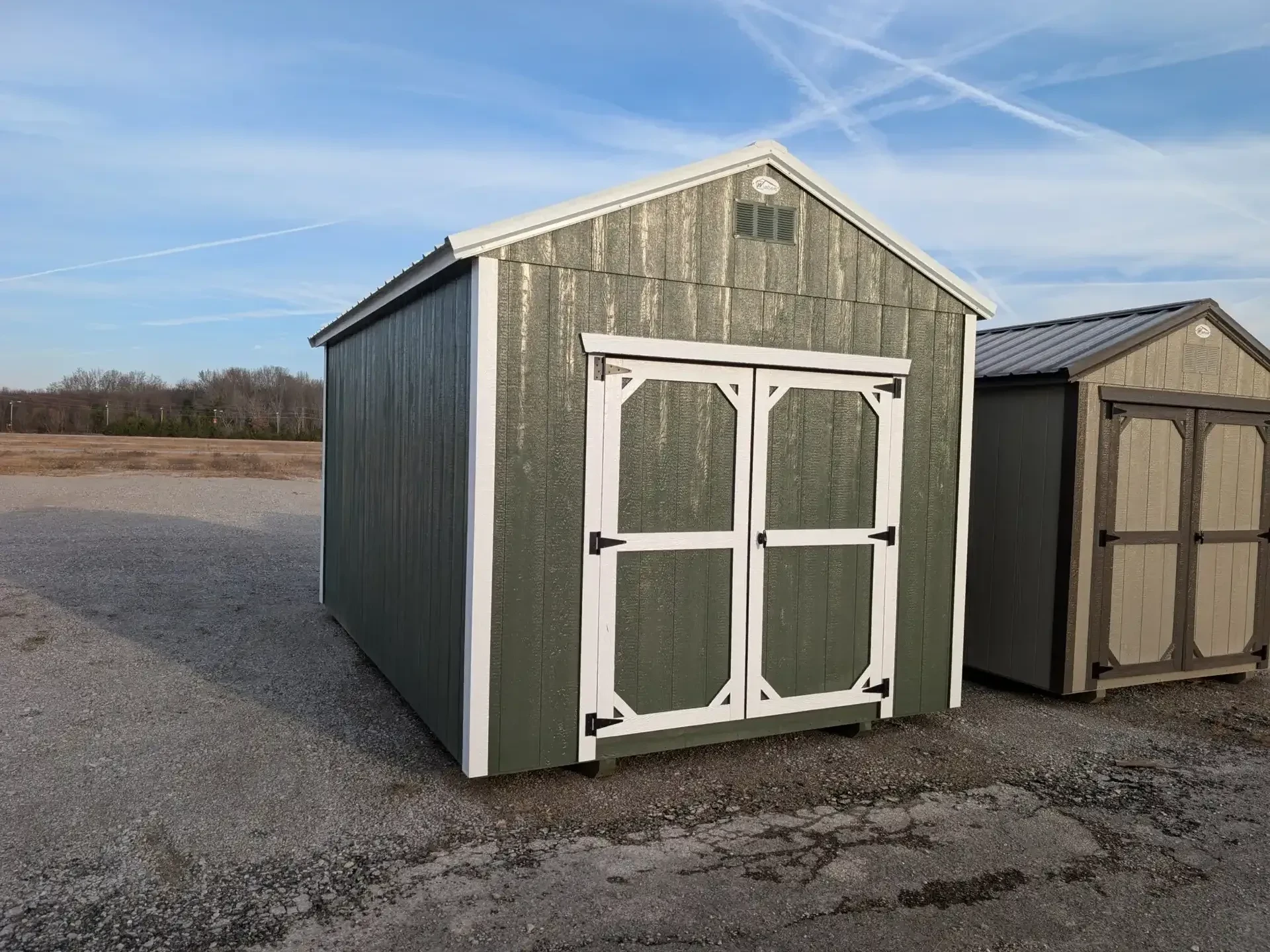 A green wood utility shed with white trim and double doors