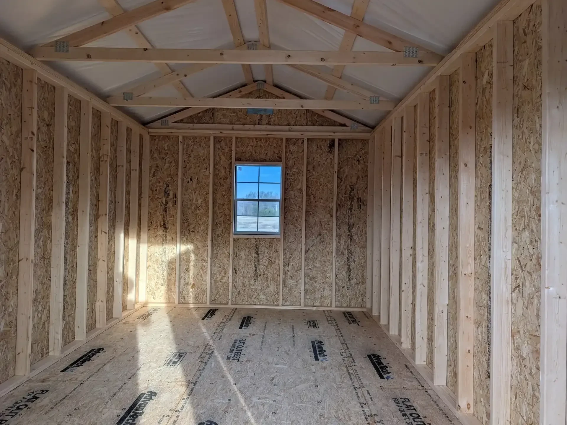 inside a wood shed with a window in the middle of the back wall