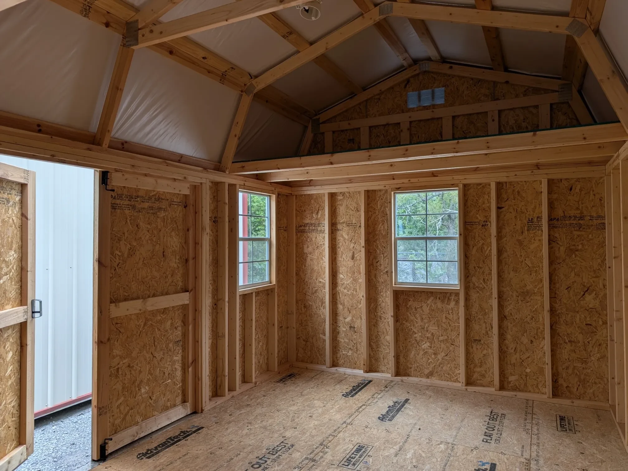 inside a wood lofted barn showing the loft and multiple windows