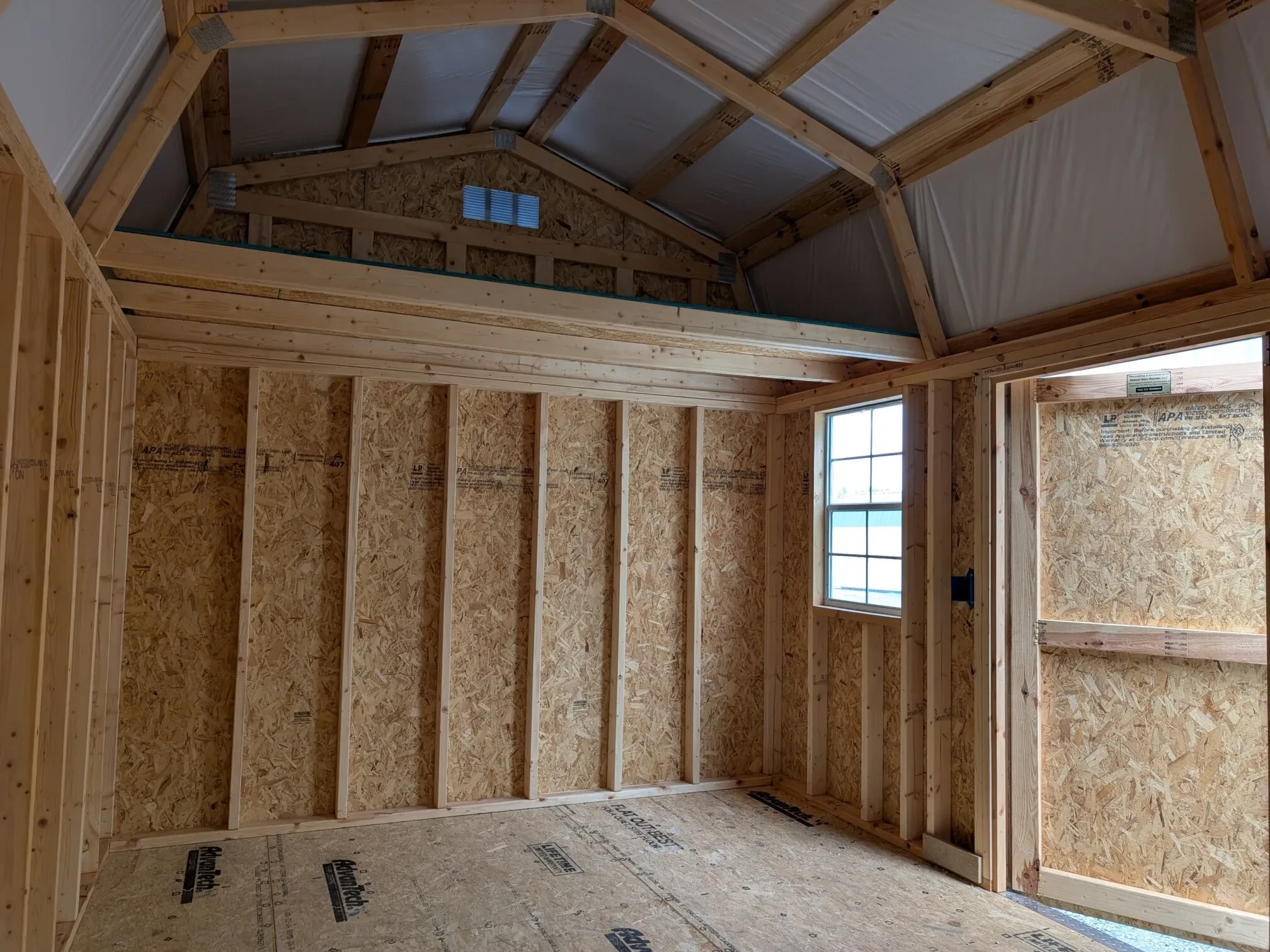 inside a lofted shed with the double doors open next to a window