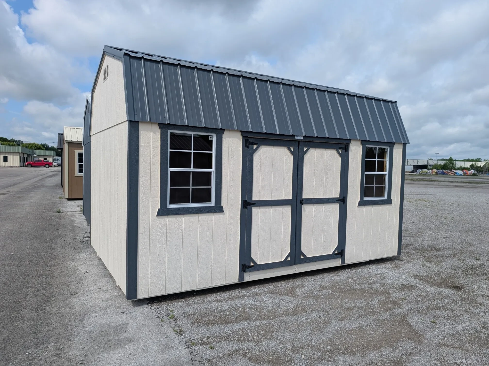 a white side lofted barn with blue trim and two windows