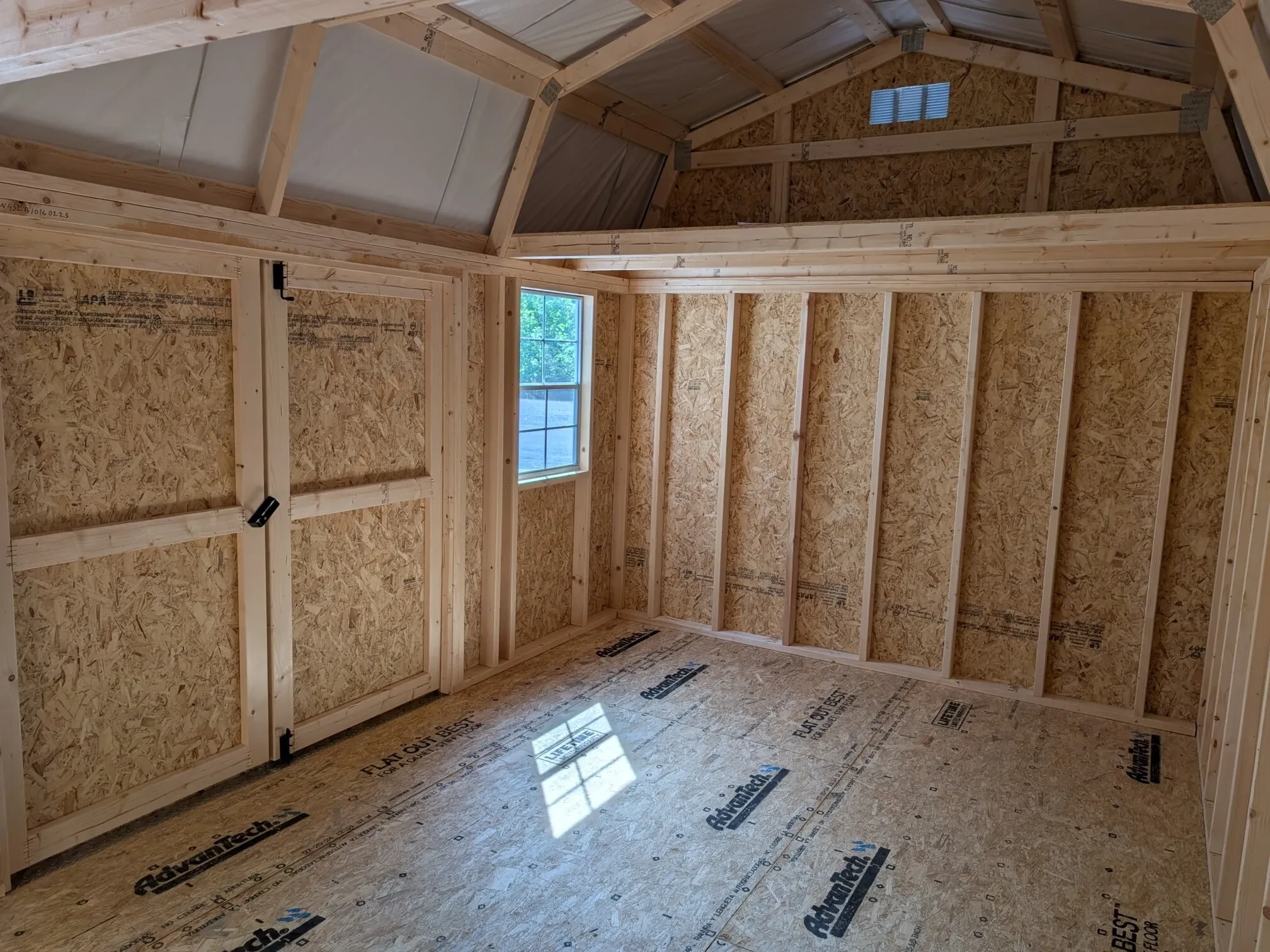 inside a wood side lofted barn with a window and a loft in sight