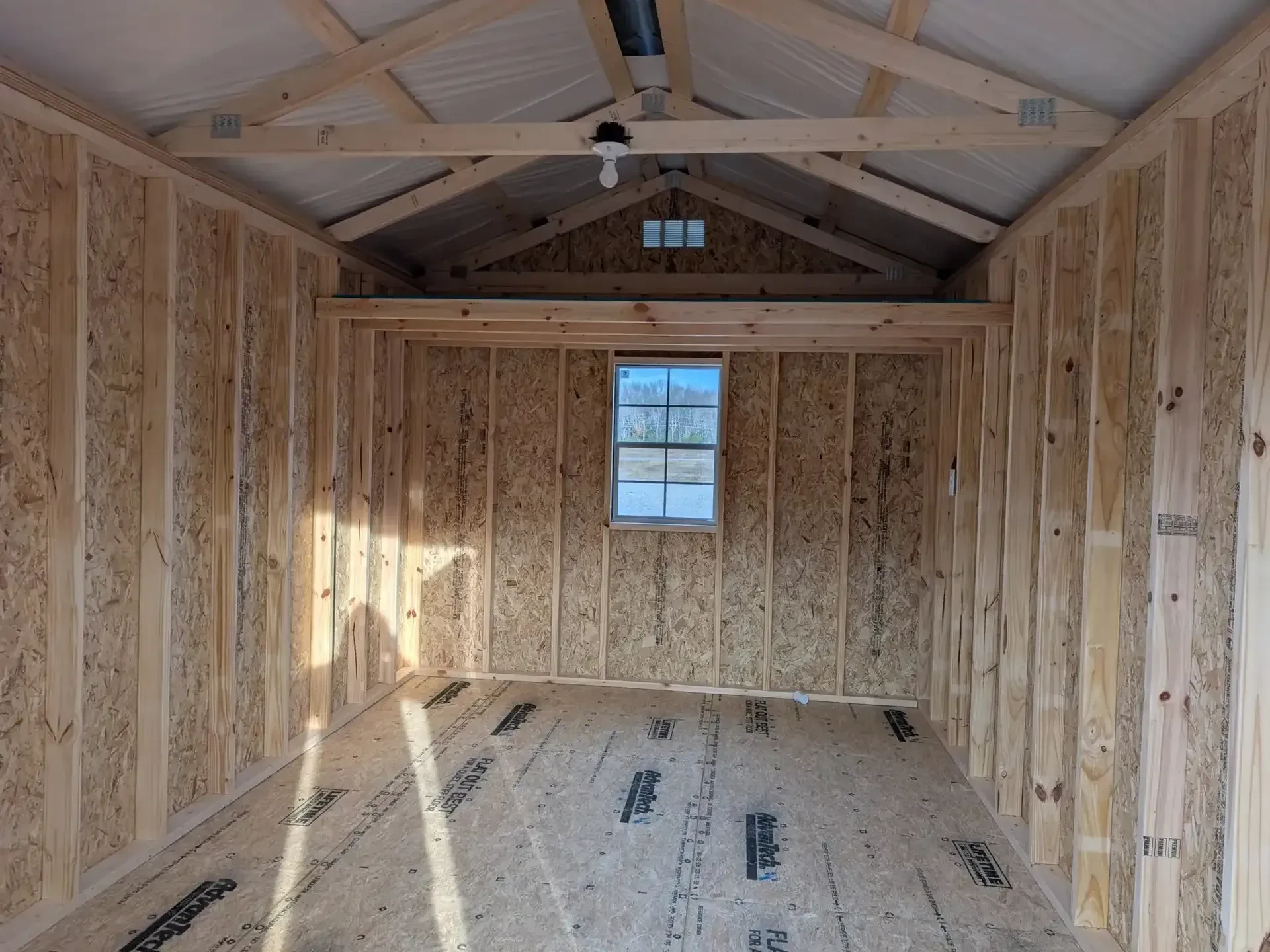 inside a wood shed with a loft and a window in the back wall
