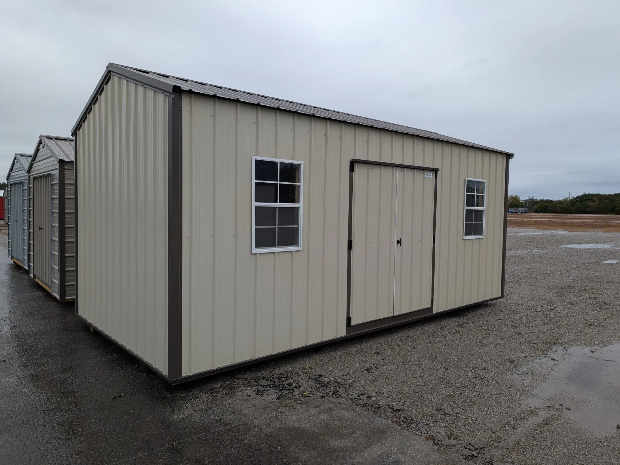 a metal garden shed with two windows and double doors