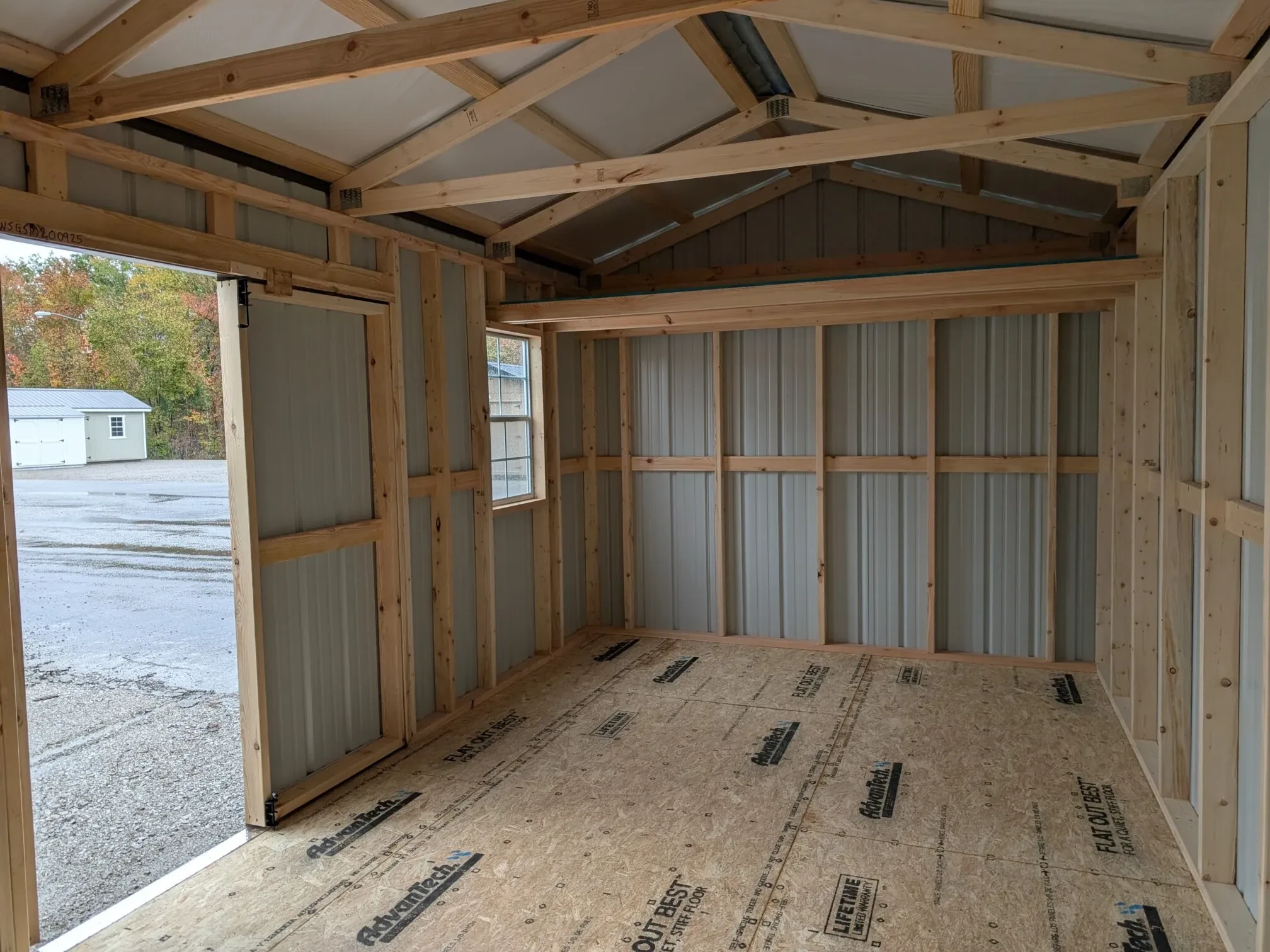 inside a metal shed showing a door open and a loft and a window