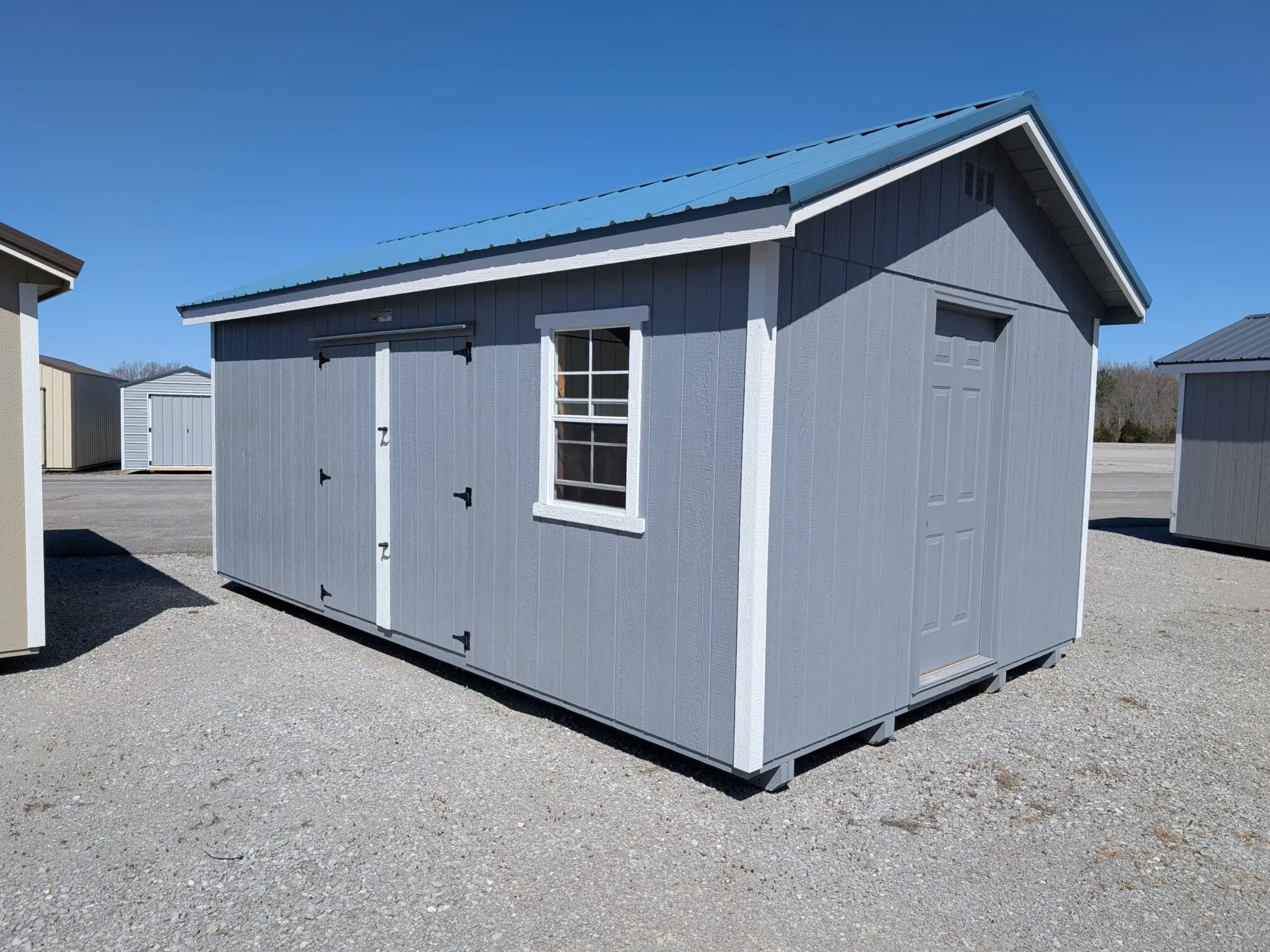 a bshed with white trim and double doors, a walk-in door, and a window