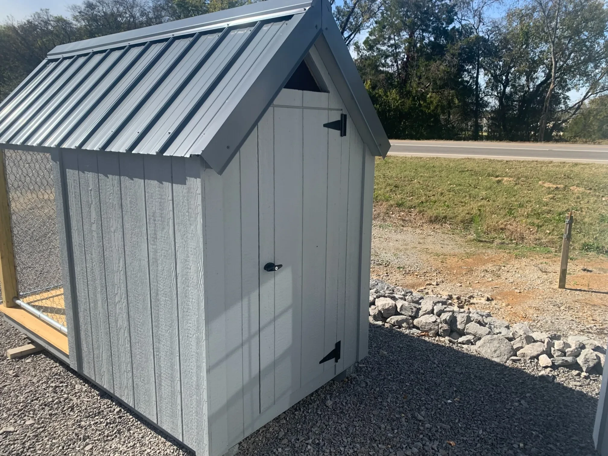 a gray dog house with a gray metal roof and a walk in door