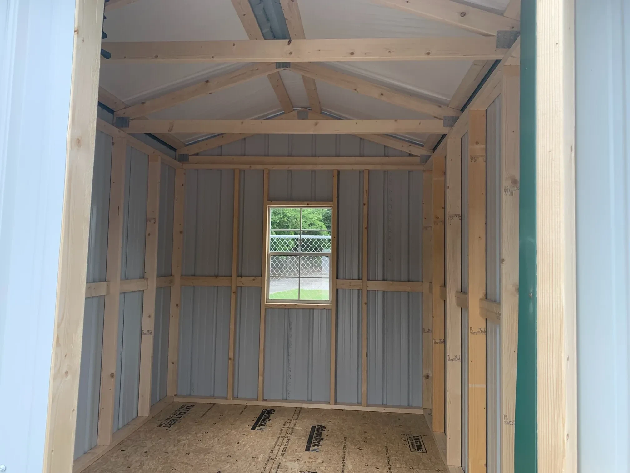 inside a metal shed with the double doors open and a window on the back wall