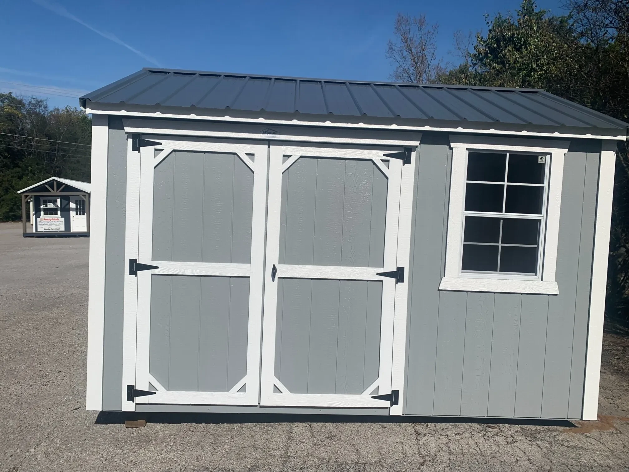 a wood garden shed with double doors and a window next to it