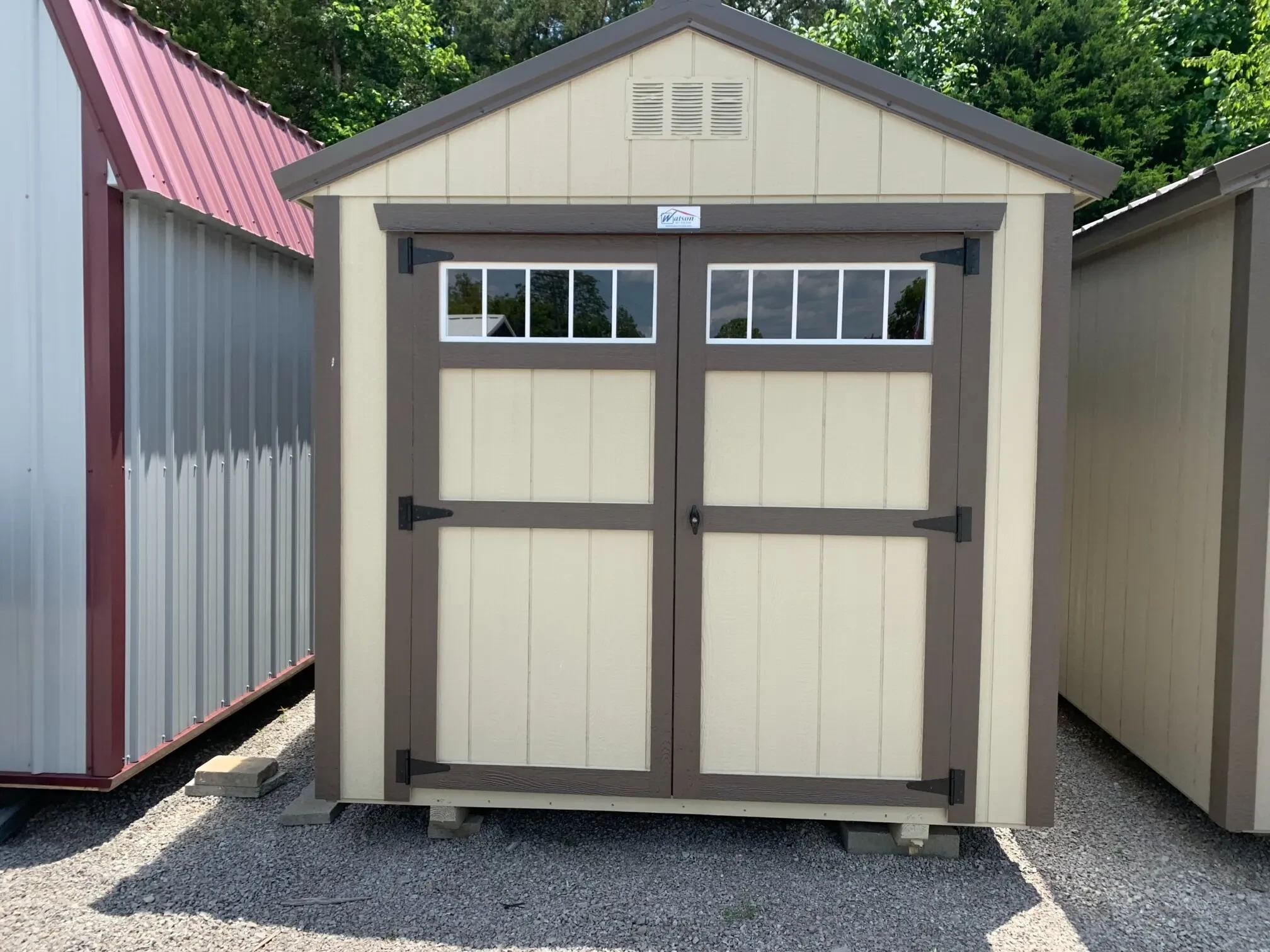 a wood shed with double doors with transom windows on them