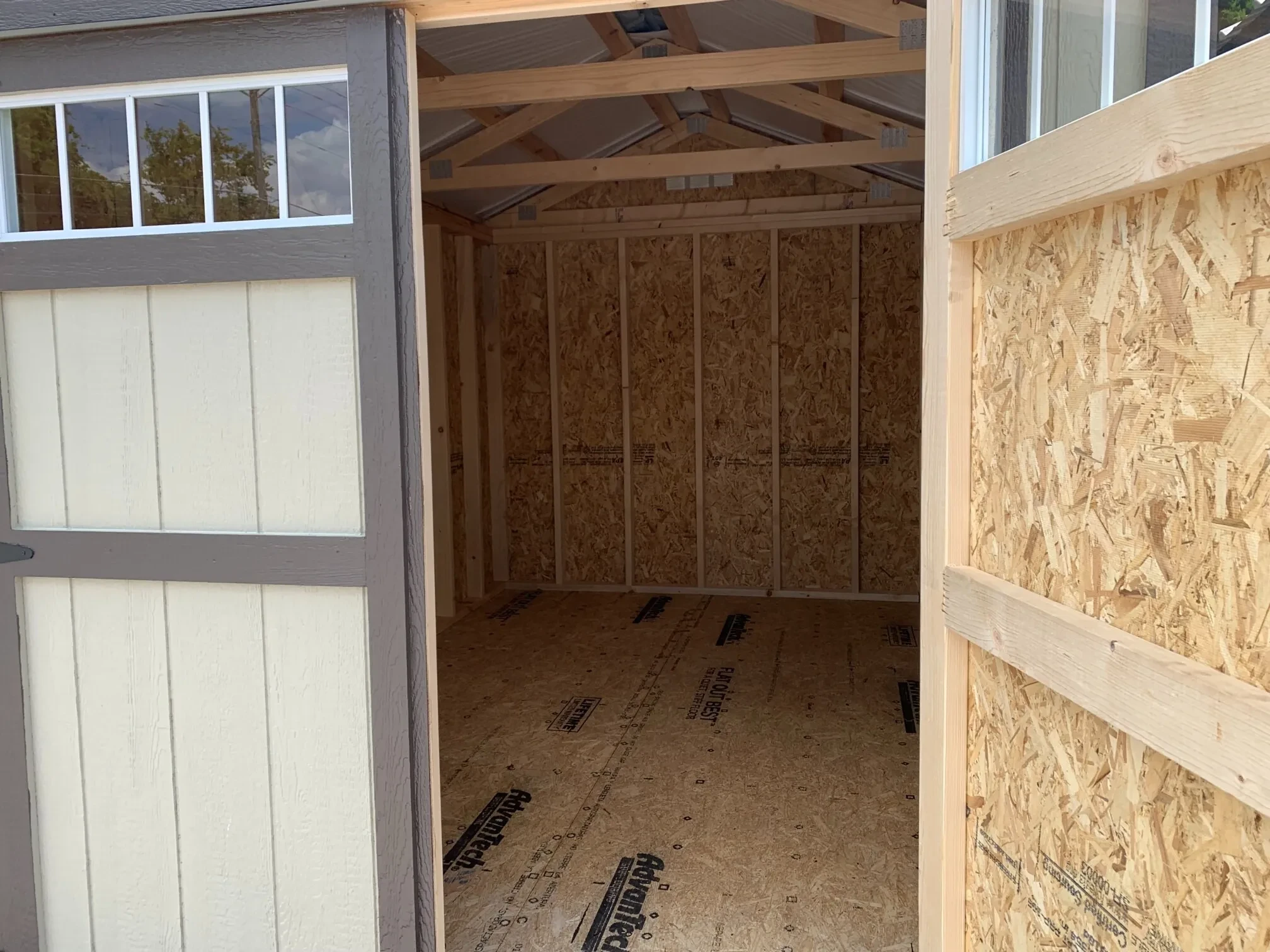 inside a wood shed with a door open with transom windows