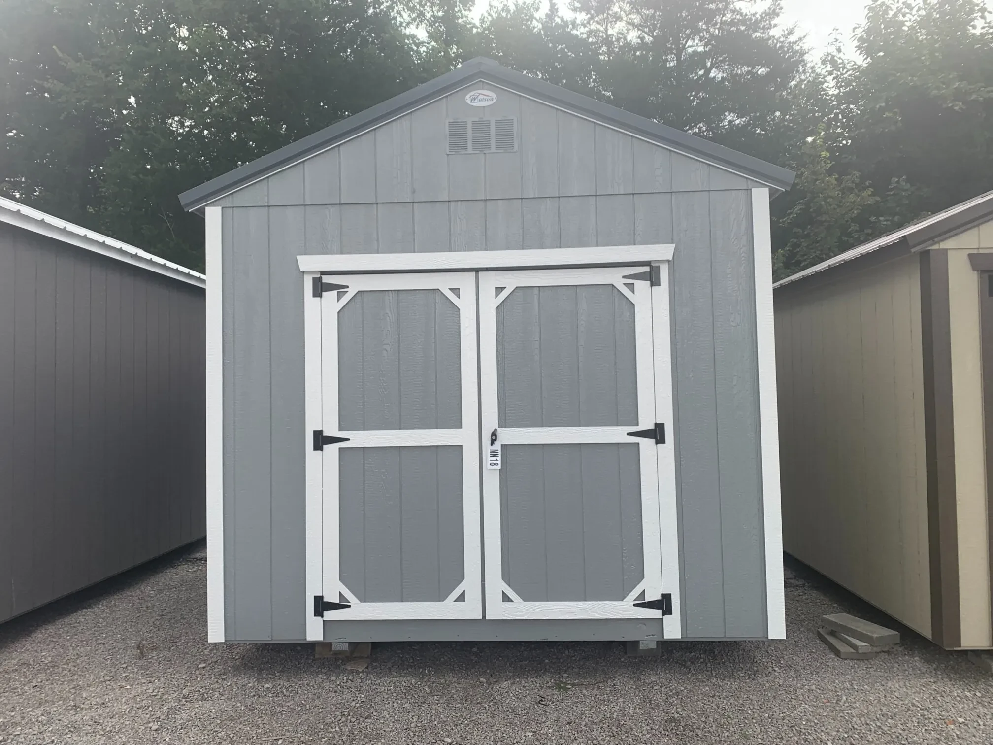 a light gray wood utility shed with double doors