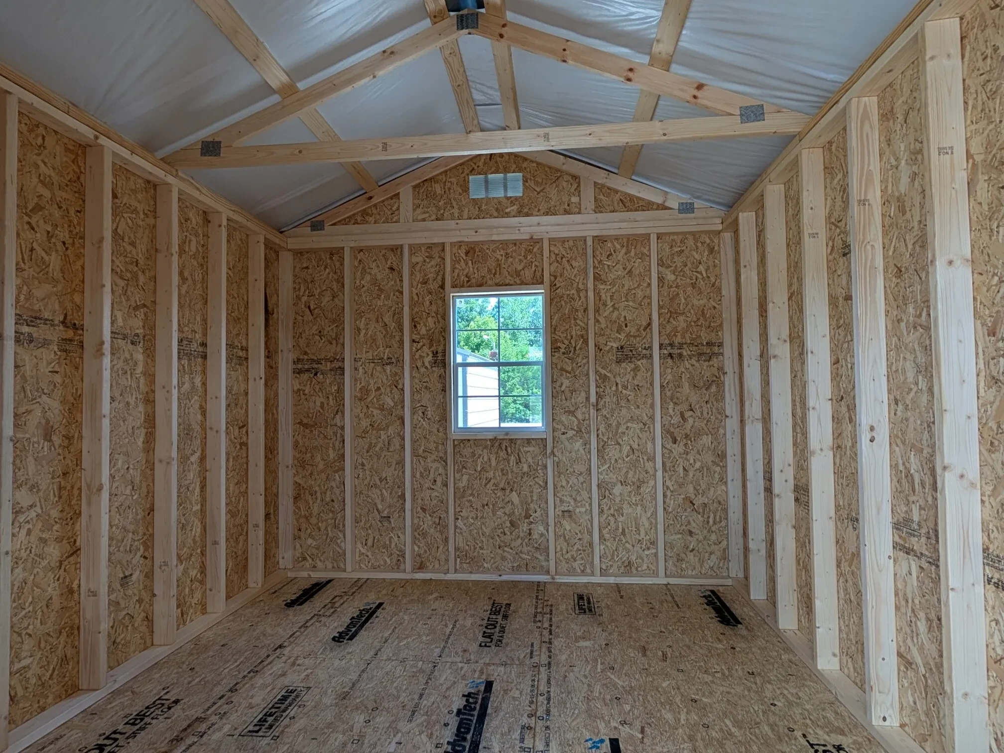 inside a wood utility shed with a window on the back wall