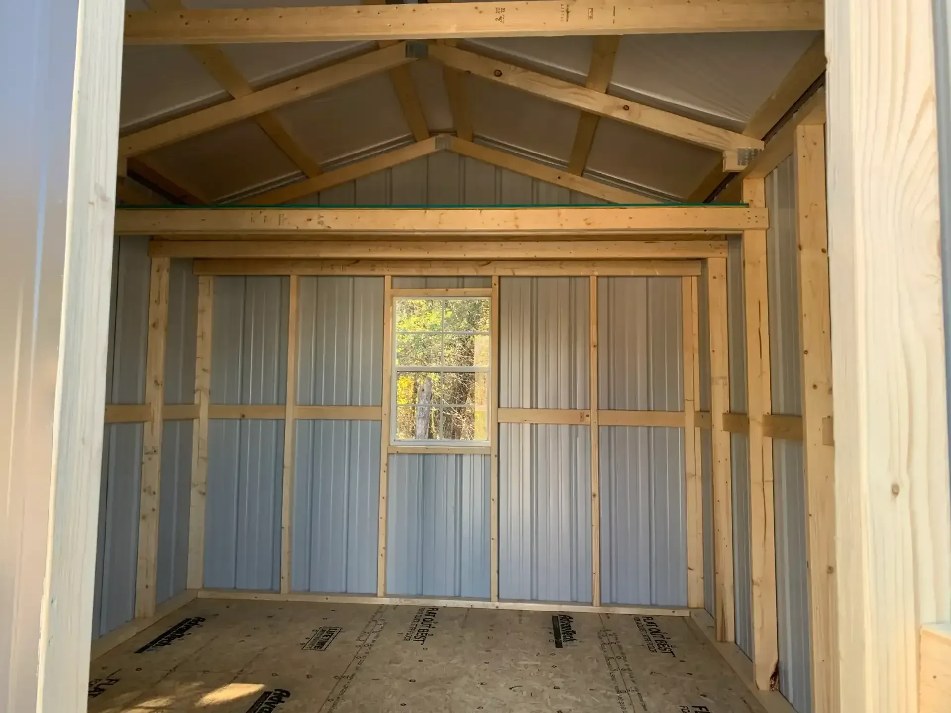 inside a metal shed with a window and loft along the back wall