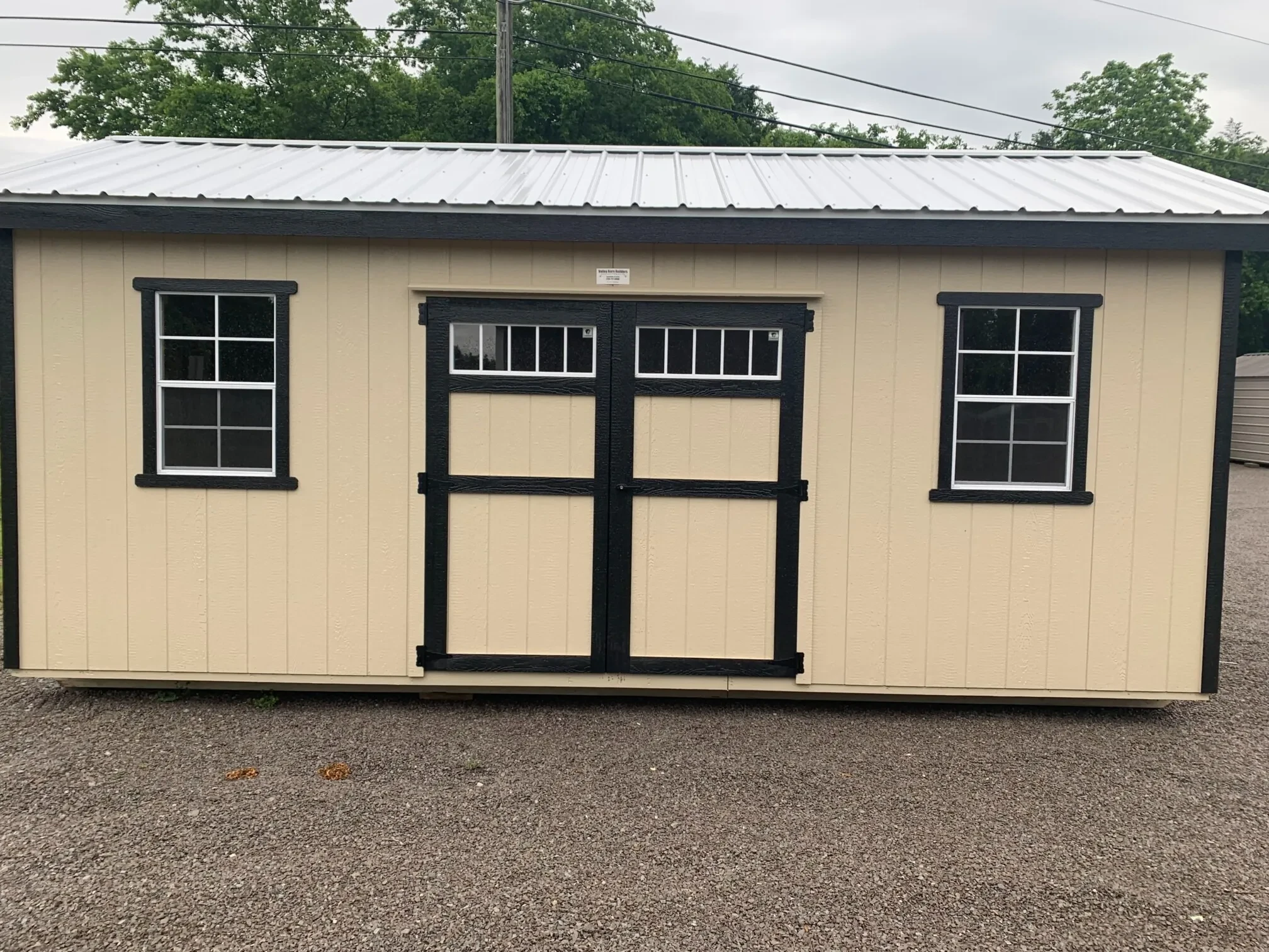 a stone colored garden shed with double doors with transom windows and 2x3 windows