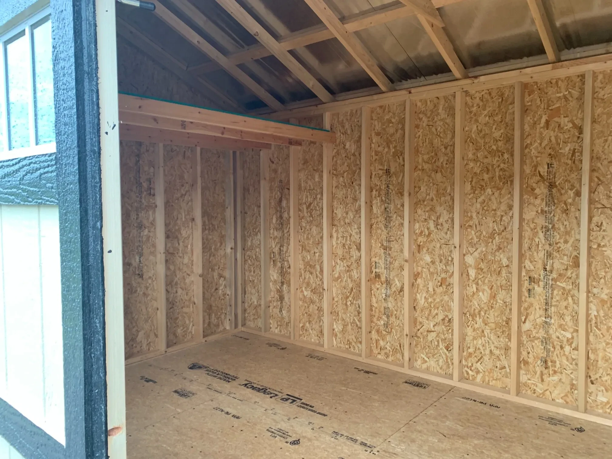 inside a wood garden shed with a loft on the left side