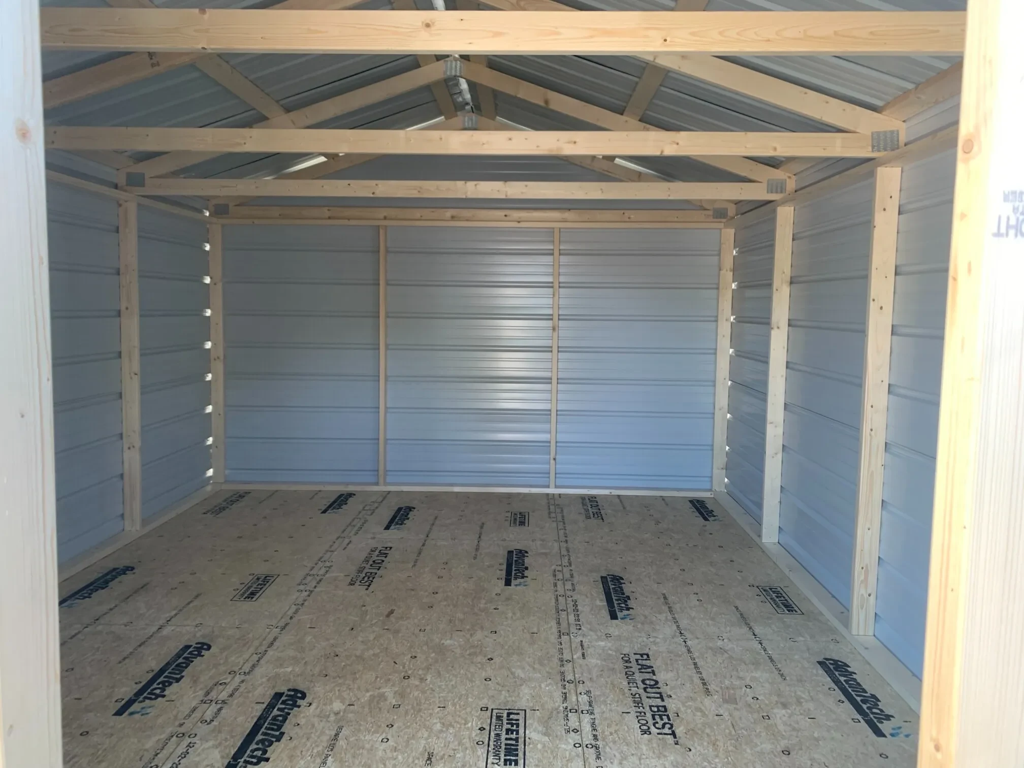 inside a wide metal shed showing the wood framing
