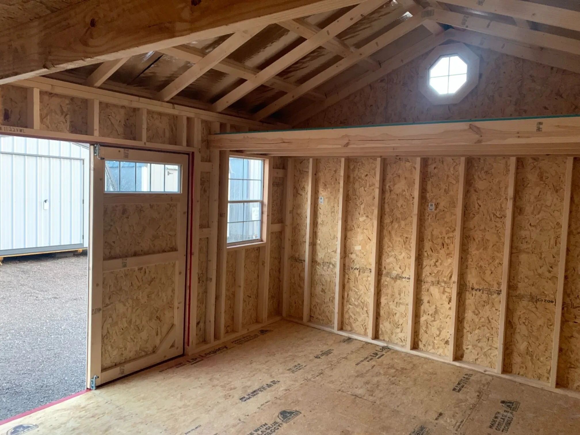 inside a wood garden shed with a window and a loft and an octagon window