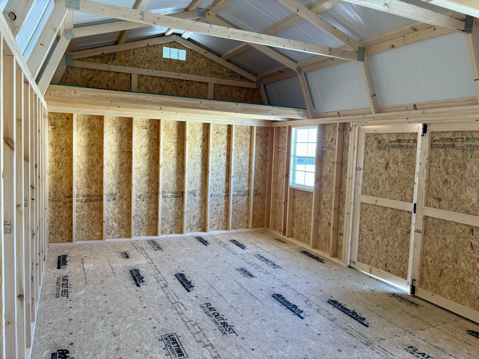inside a lofted barn with a window, double doors, and a loft