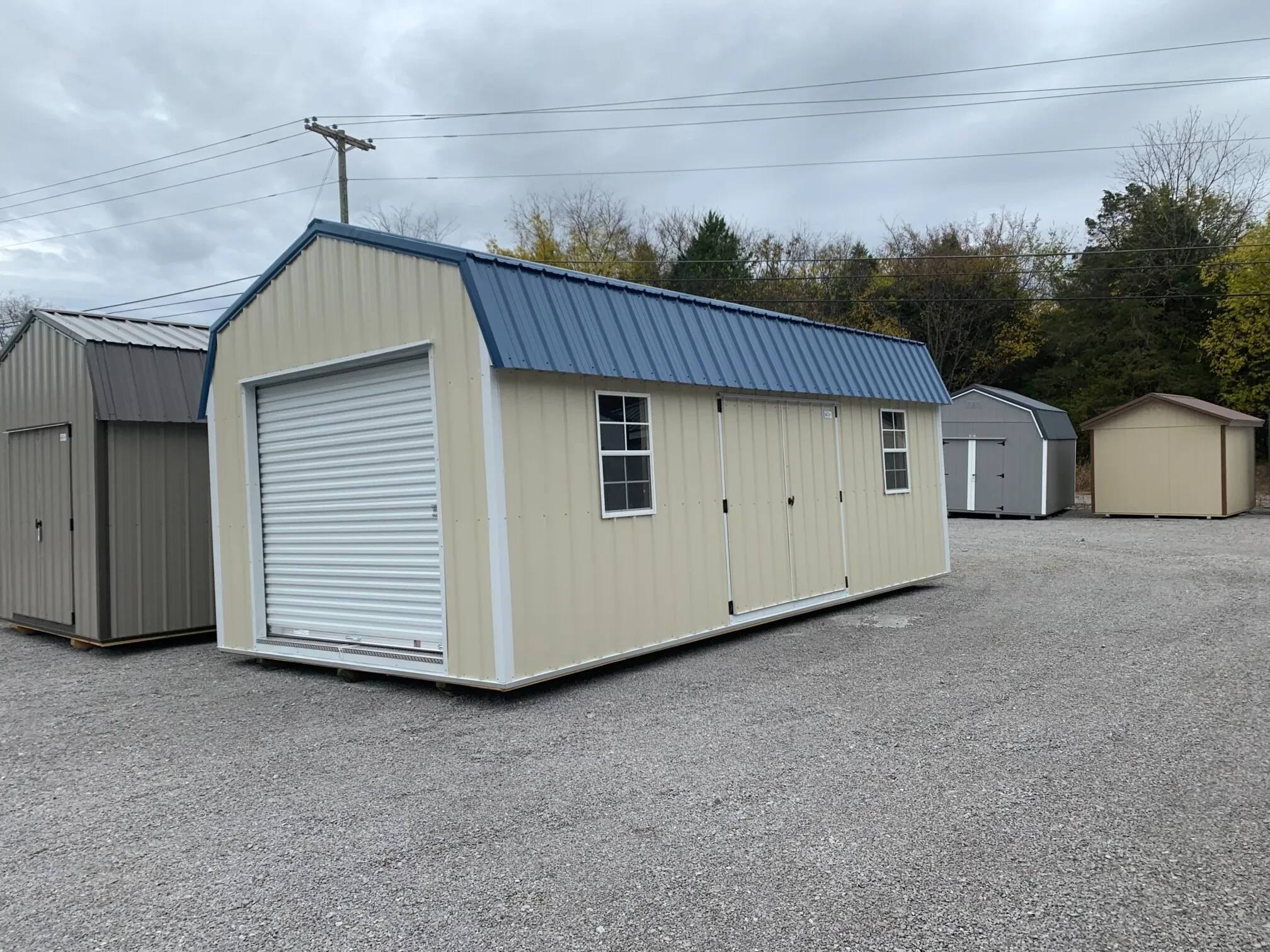 A metal lofted garage barn with a rollup door and double doors and two windows