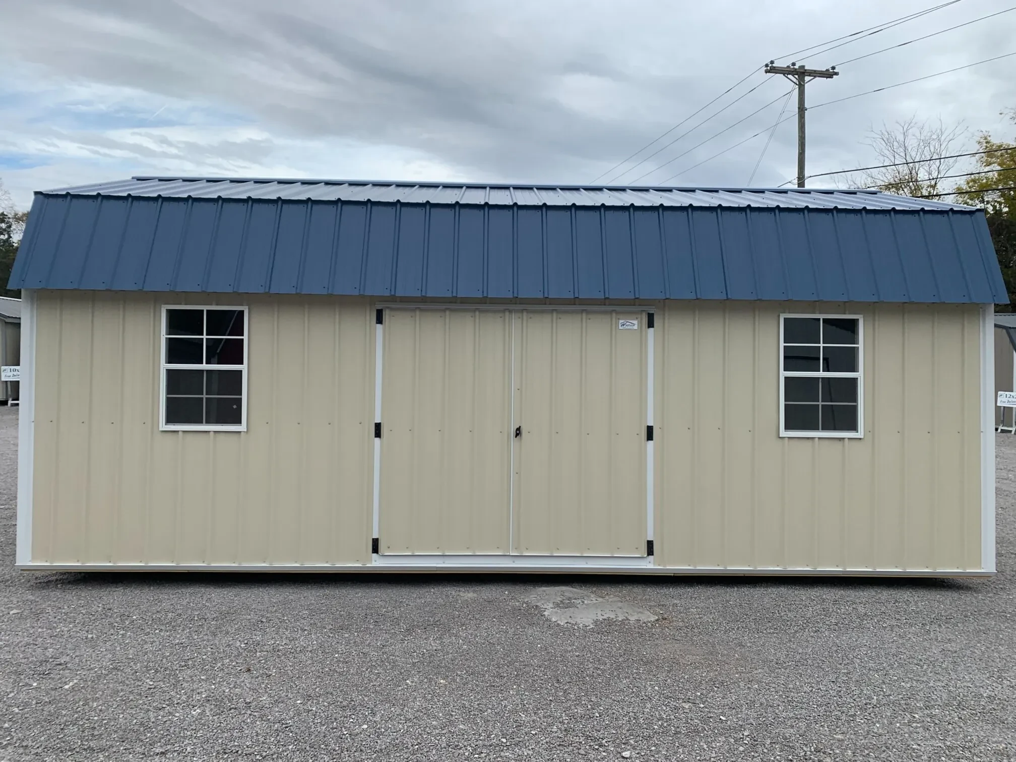 the side of a metal lofted garage showing the double doors and the two windows