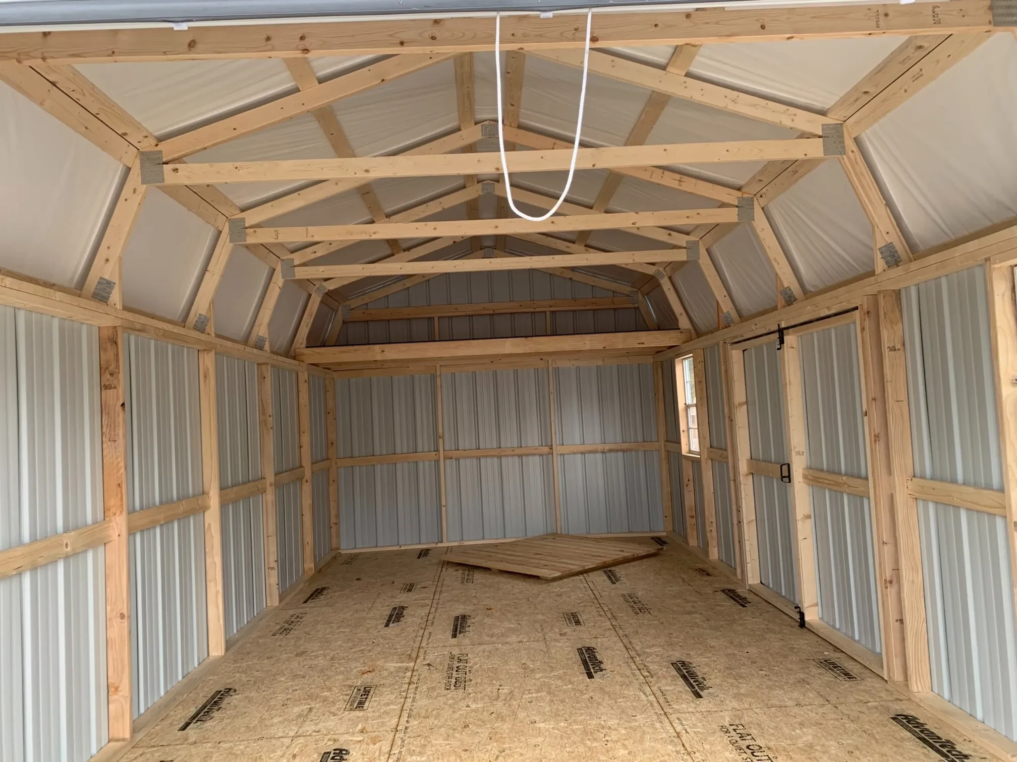 the inside of a metal lofted garage showing the loft and the insulation under the roof