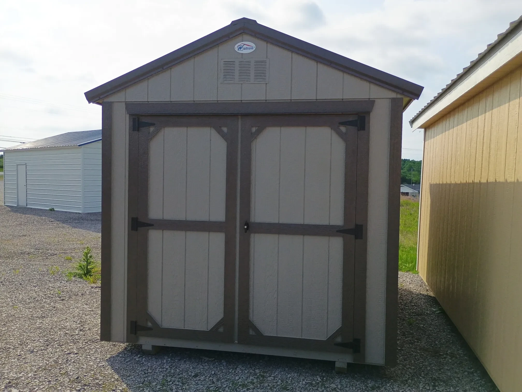 a wood shed painted clay with double doors and bronze trim